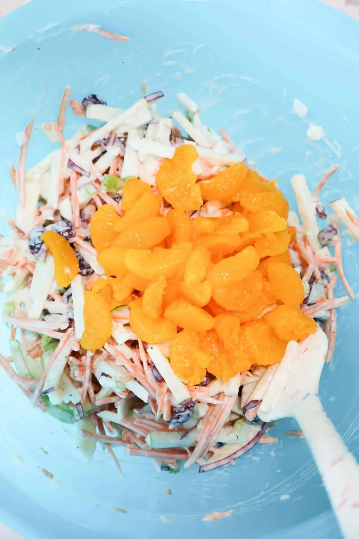 mandarin segments on top of carrot apple salad in a mixing bowl