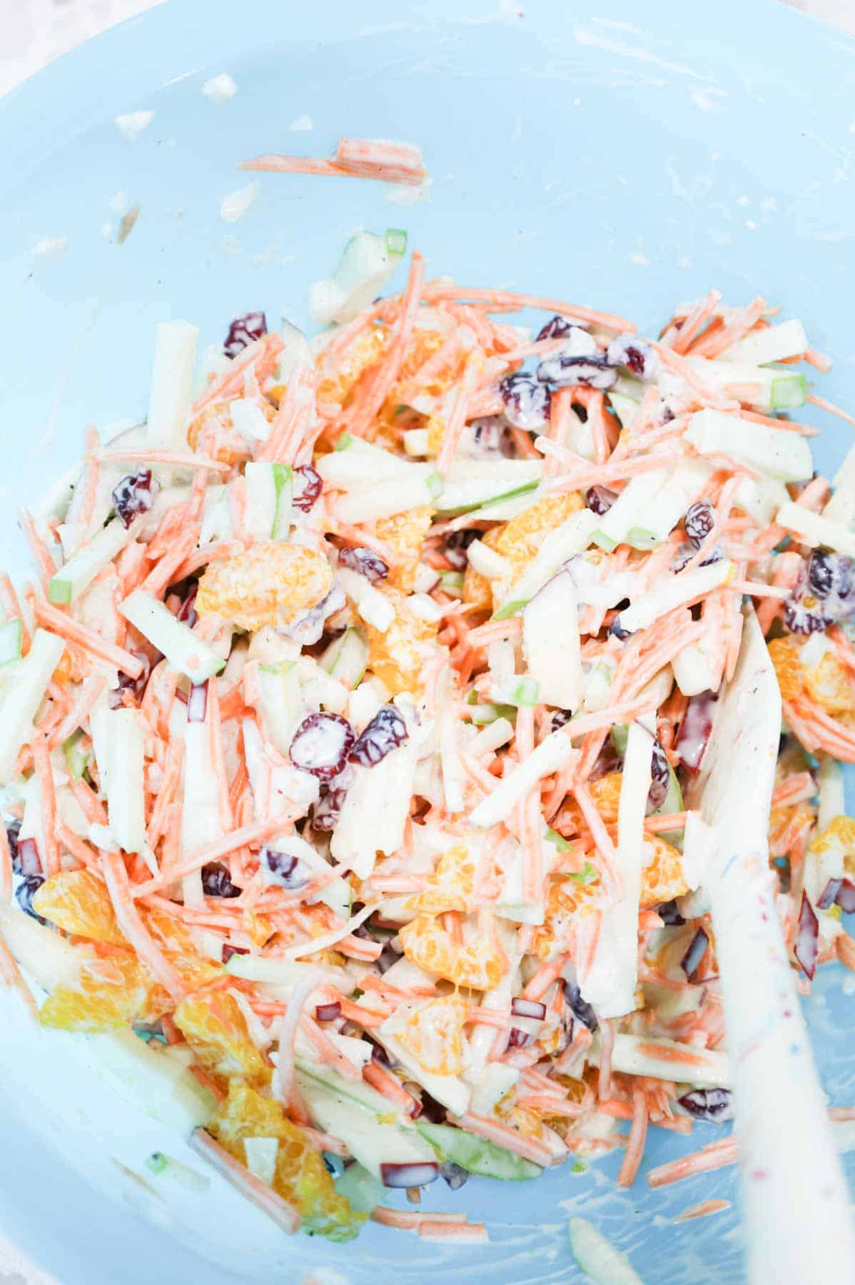 carrot apple salad being stirred in a bowl