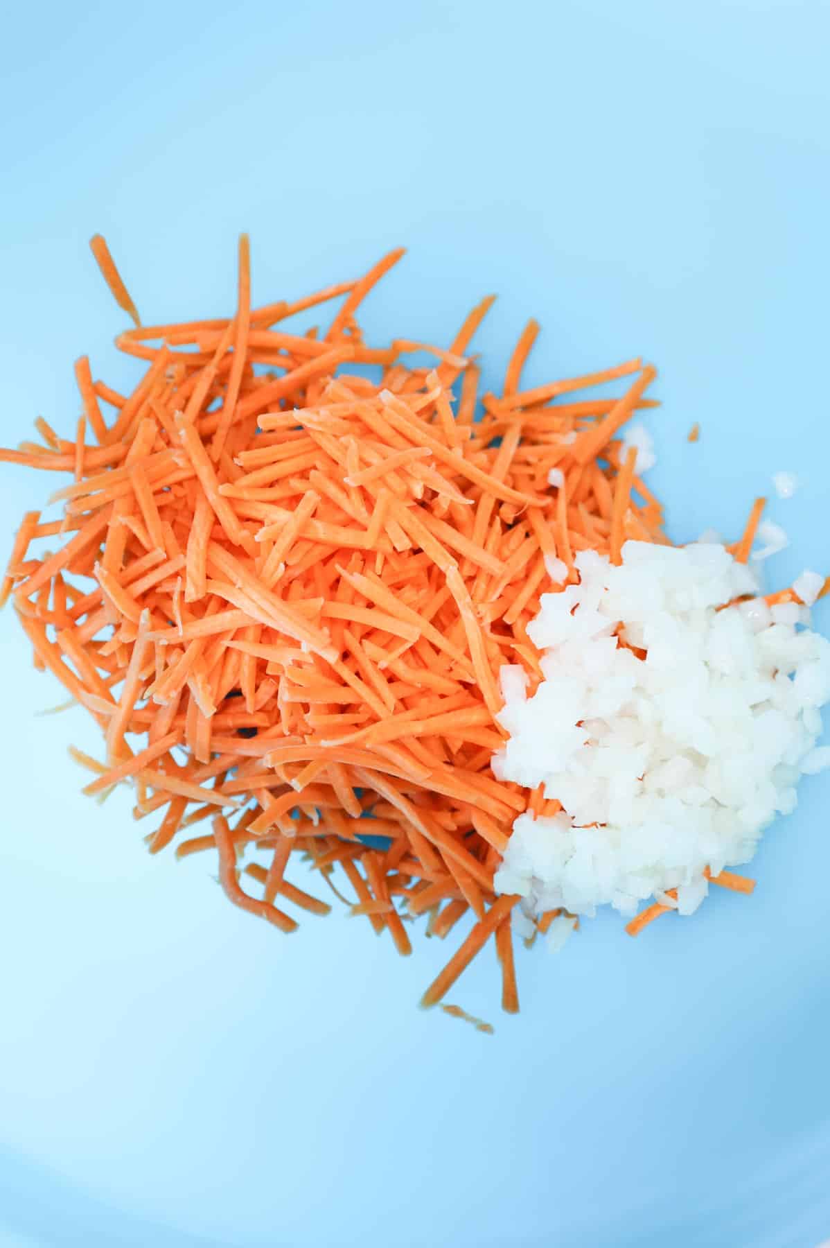 matchstick carrots and diced onions in a mixing bowl
