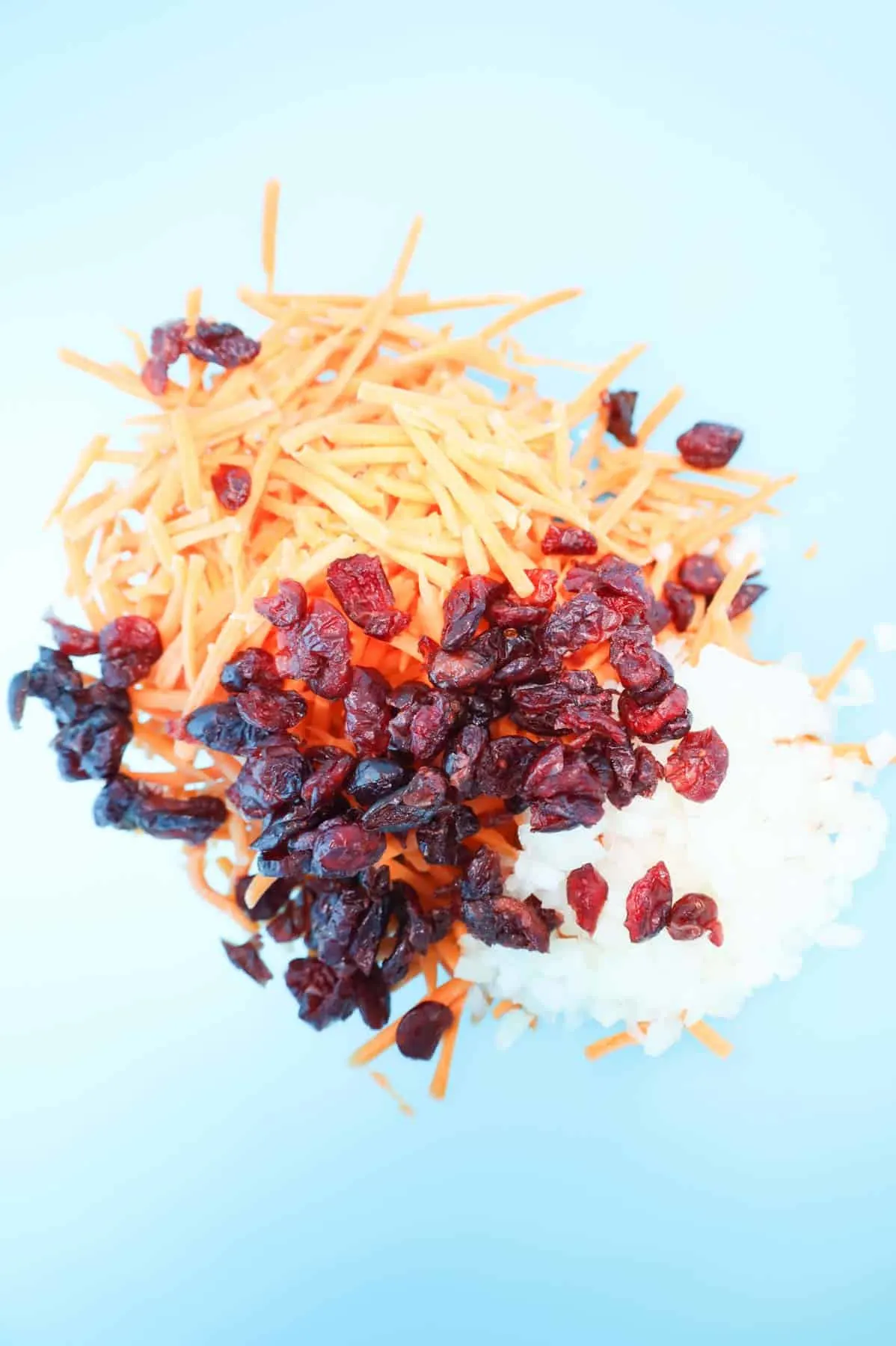 matchstick carrots, dried cranberries and diced onions in a mixing bowl