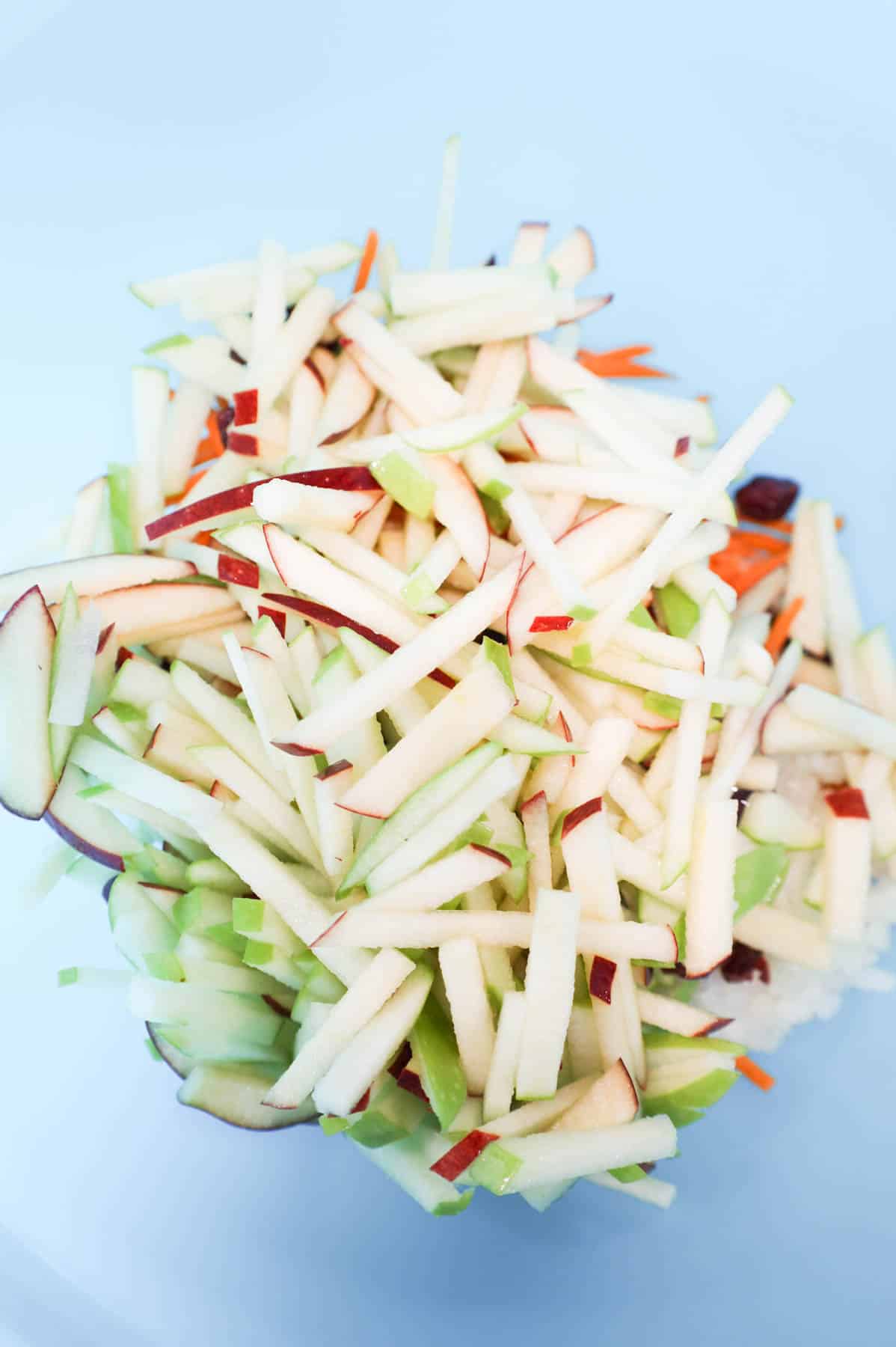 matchstick sliced apples add to mixing bowl with carrots, cranberries and onions