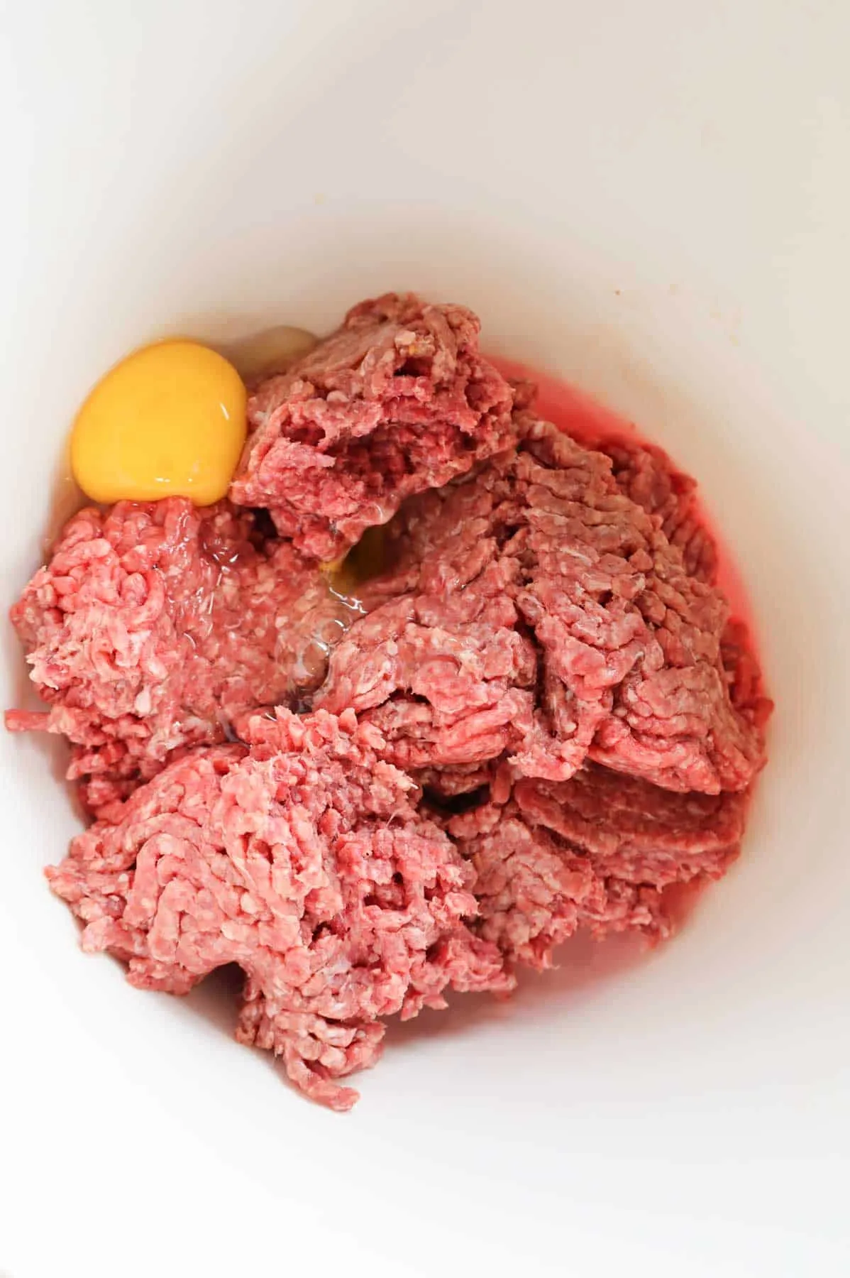 eggs, milk and lean ground beef in a bowl