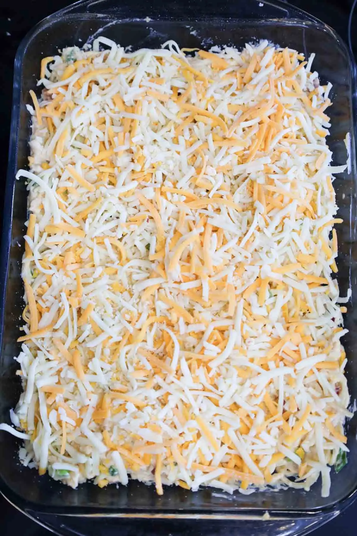 shredded chicken on top of creamy spaghetti in a baking dish
