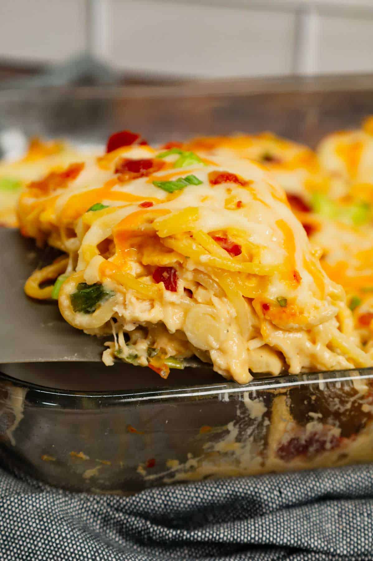 Crack Chicken Spaghetti is a delicious baked pasta recipe with a creamy sauce and loaded with shredded chicken, crumbled bacon, chopped green onions, ranch dressing mix and shredded cheddar and mozzarella cheese.