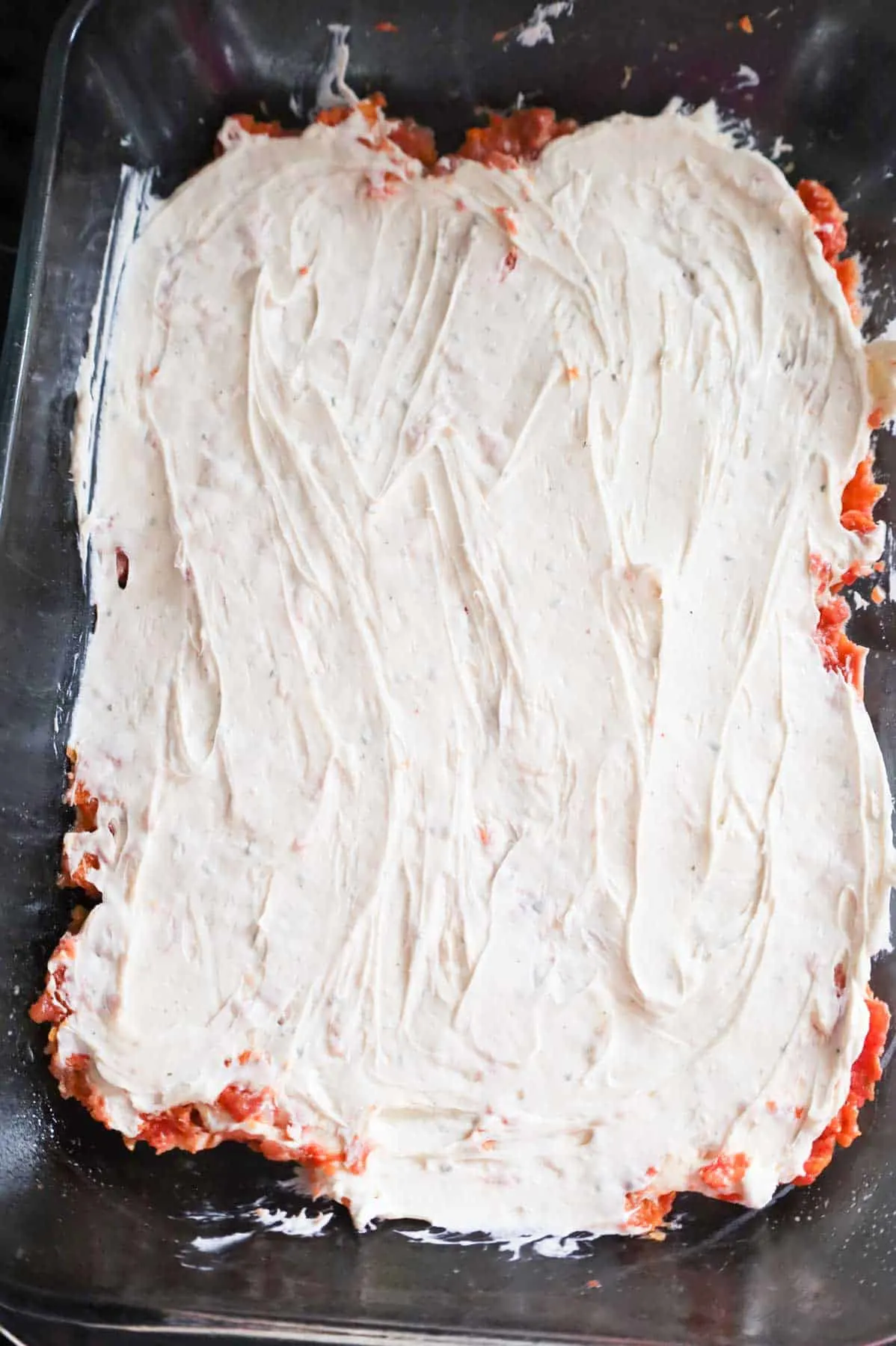 cream cheese mixture spread on top of meat mixture in a baking dish