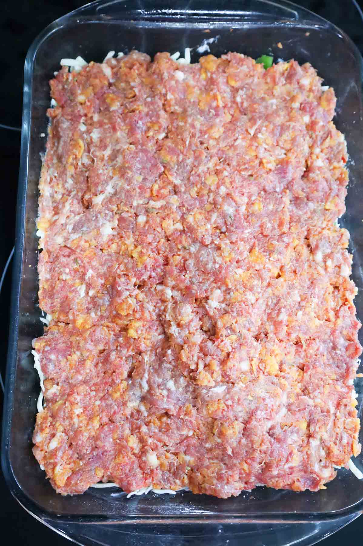sausage and ground beef mixture forms the top layer of a meatloaf casserole in a baking dish