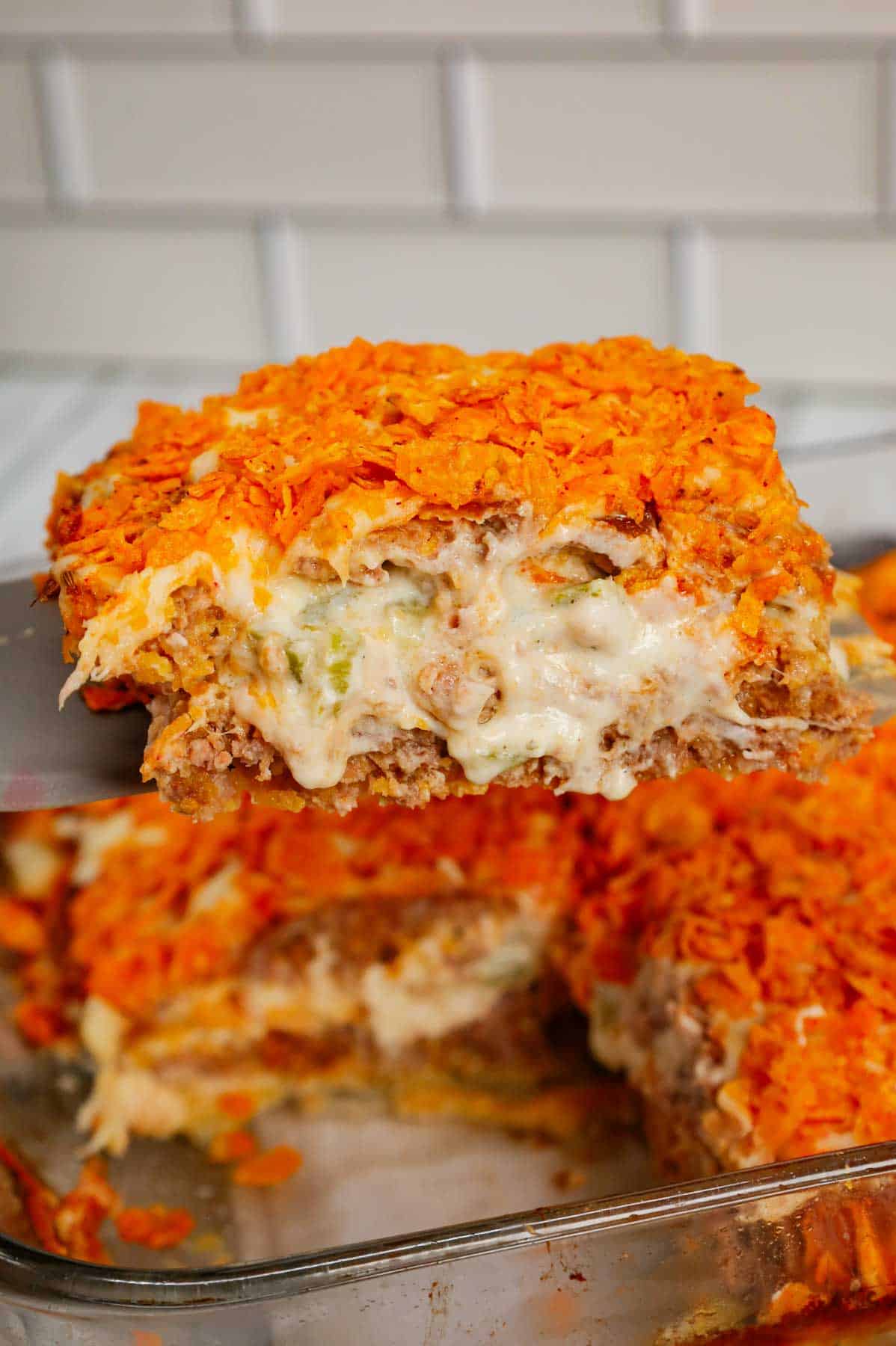 Dorito Meatloaf Casserole is a hearty dish with layers of ground beef and sausage meatloaf loaded with crushed Doritos, a cream cheese and ranch dressing filling and topped with cheese and more crushed Doritos.