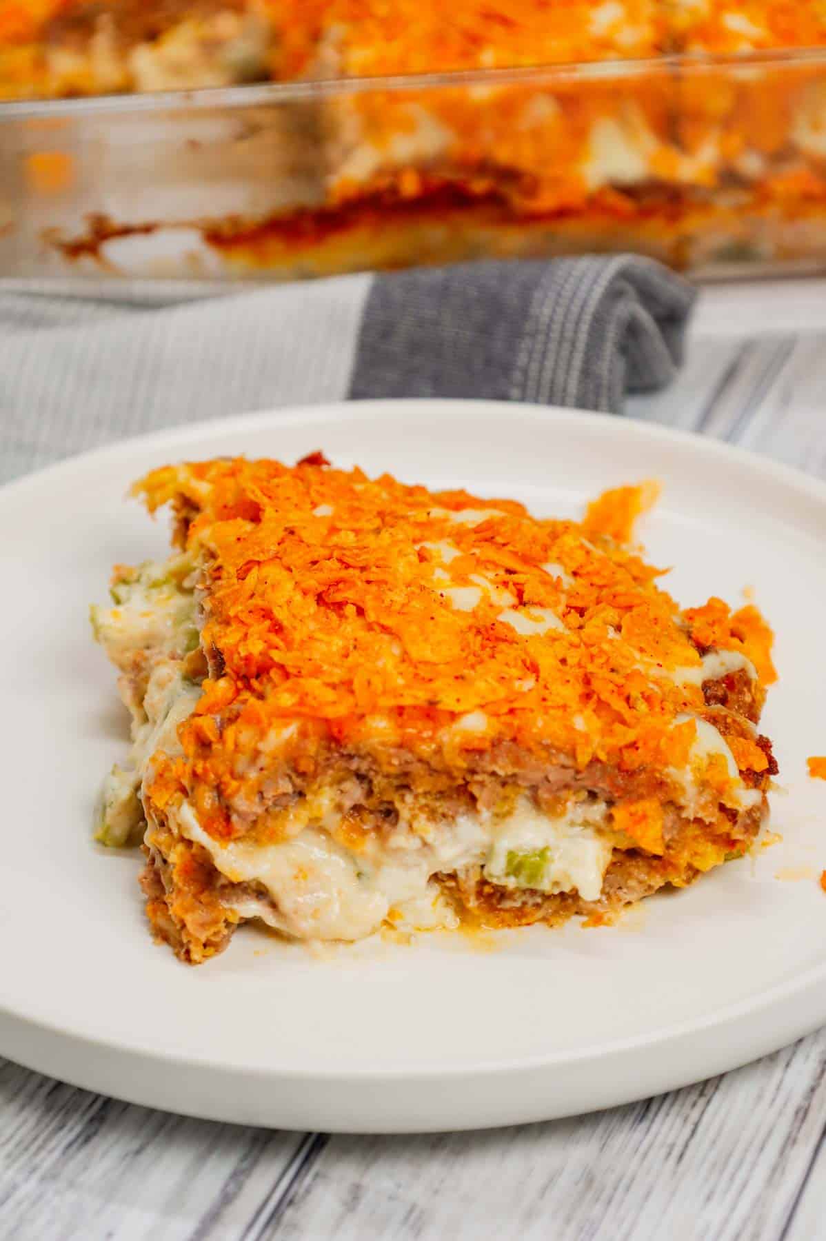 Dorito Meatloaf Casserole is a hearty dish with layers of ground beef and sausage meatloaf loaded with crushed Doritos, a cream cheese and ranch dressing filling and topped with cheese and more crushed Doritos.