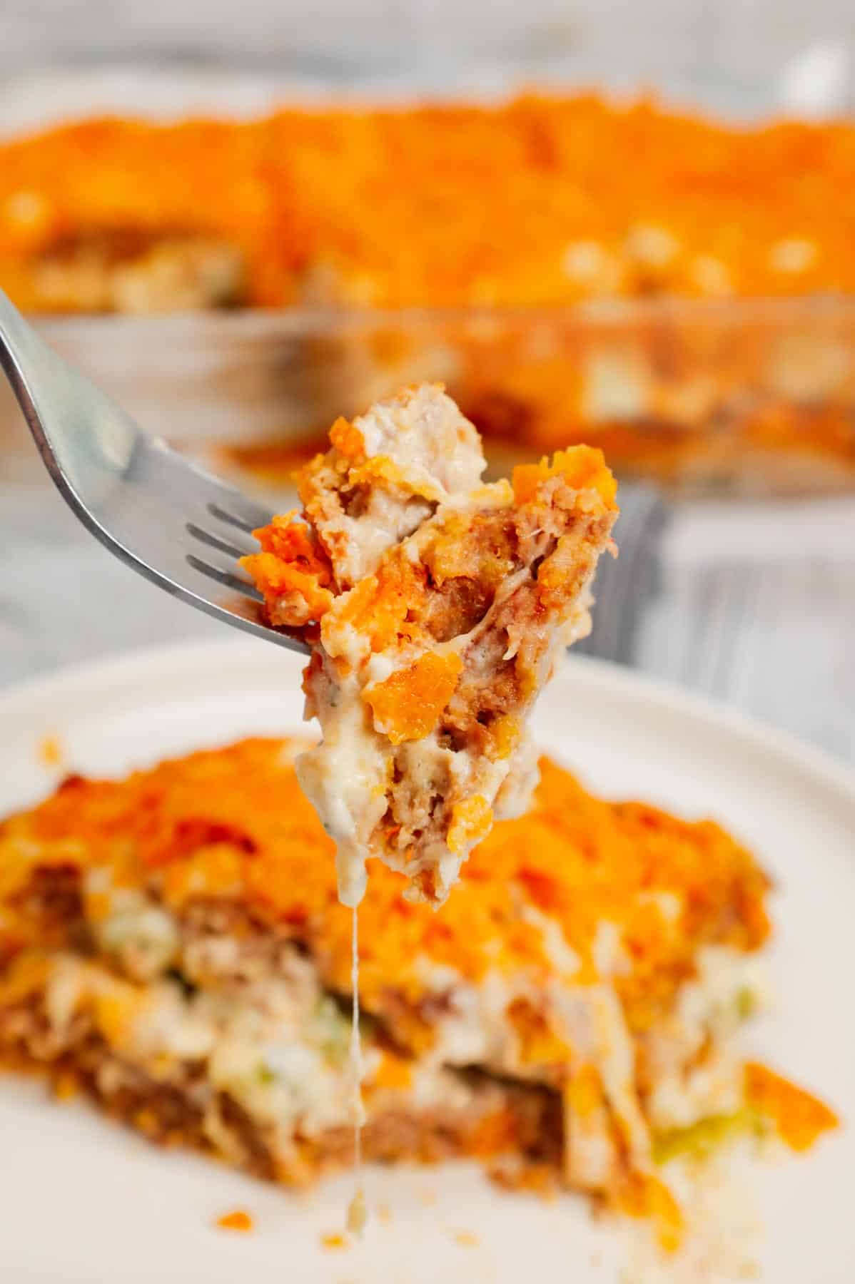 Dorito Meatloaf Casserole is a hearty dish with layers of ground beef and sausage meatloaf loaded with crushed Doritos, a cream cheese and ranch dressing filling and topped with cheese and more crushed Doritos.