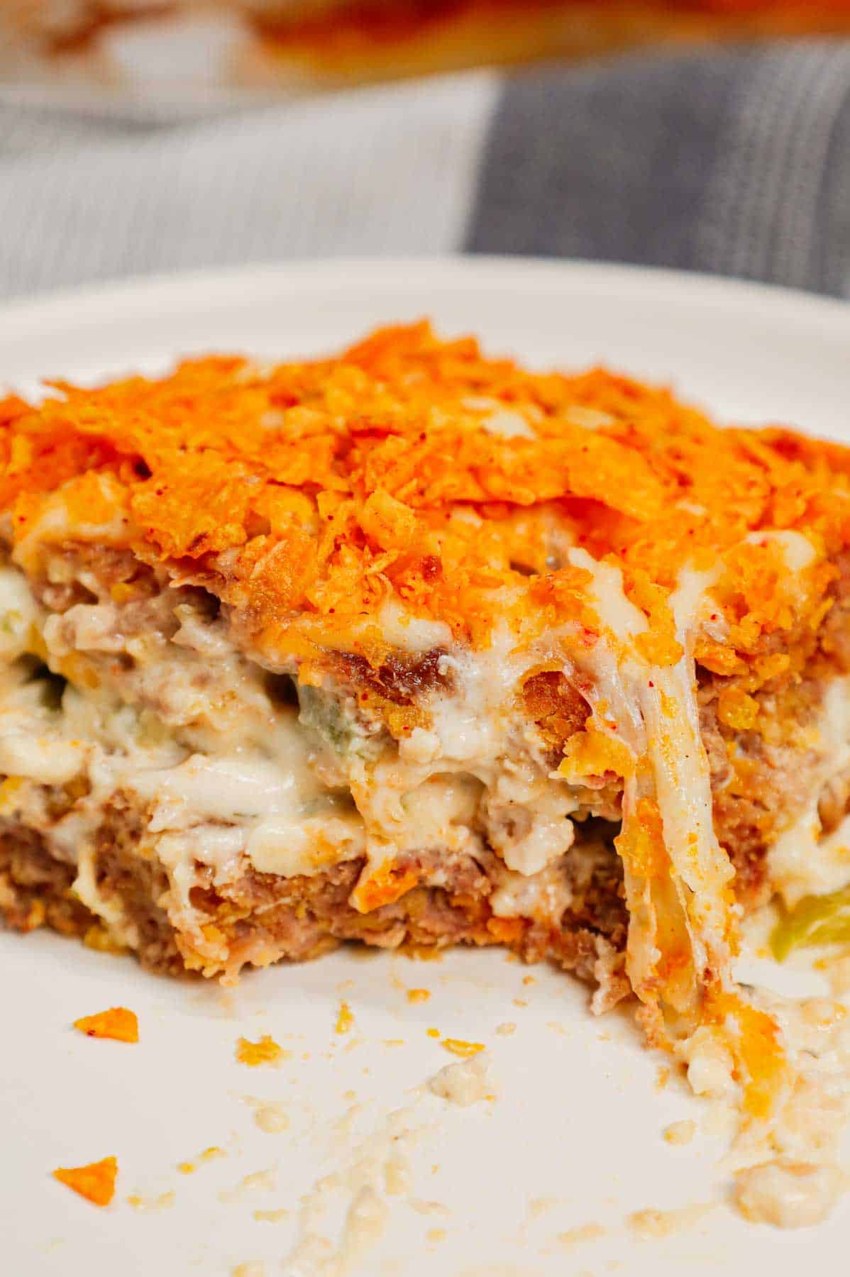 Dorito Meatloaf Casserole is a hearty dish with layers of ground beef and sausage meatloaf loaded with crushed Doritos, a cream cheese and ranch dressing filling and topped with cheese and more crushed Doritos.