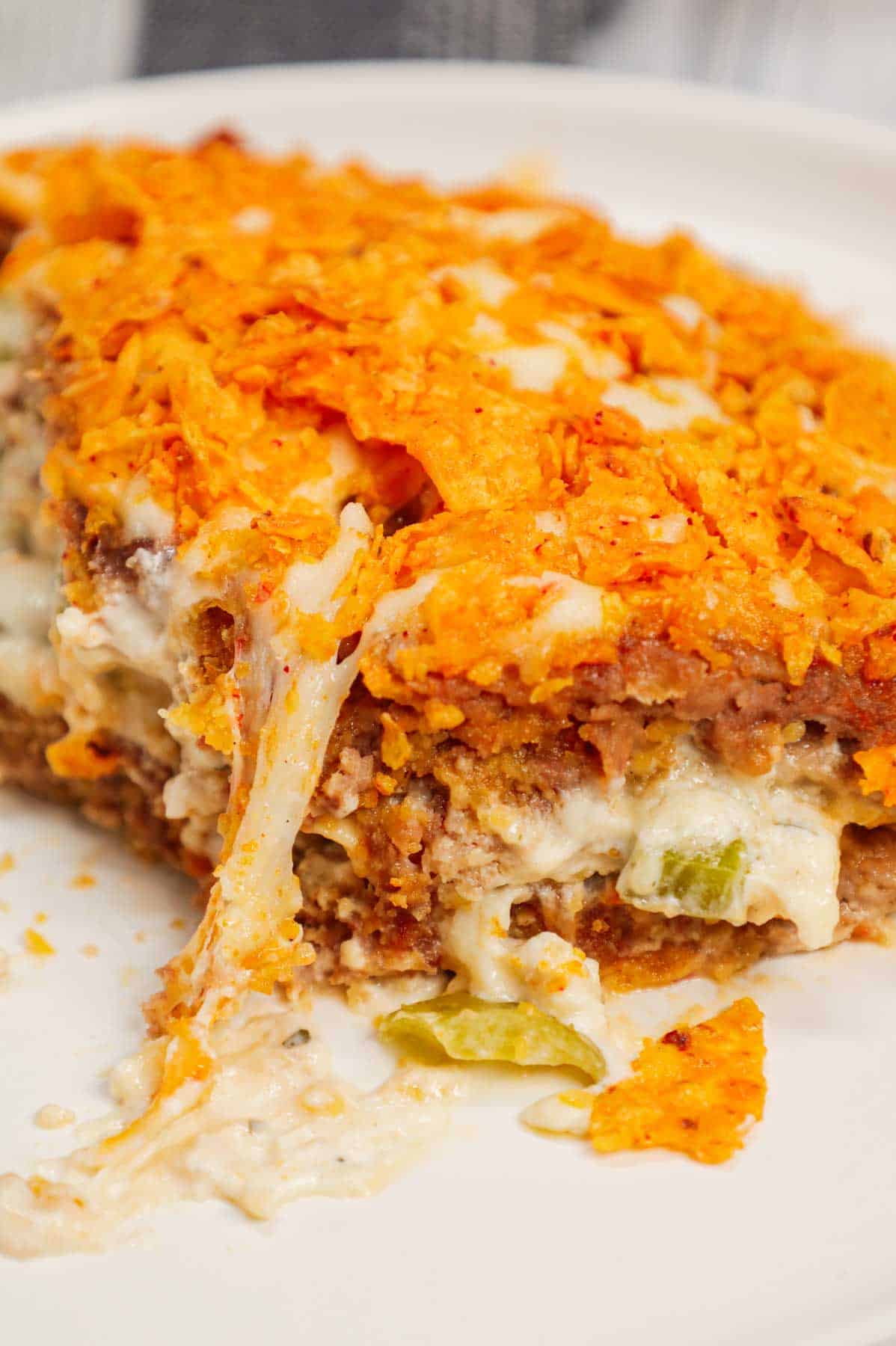 Dorito Meatloaf Casserole is a hearty dish with layers of ground beef and sausage meatloaf loaded with crushed Doritos, a cream cheese and ranch dressing filling and topped with cheese and more crushed Doritos.