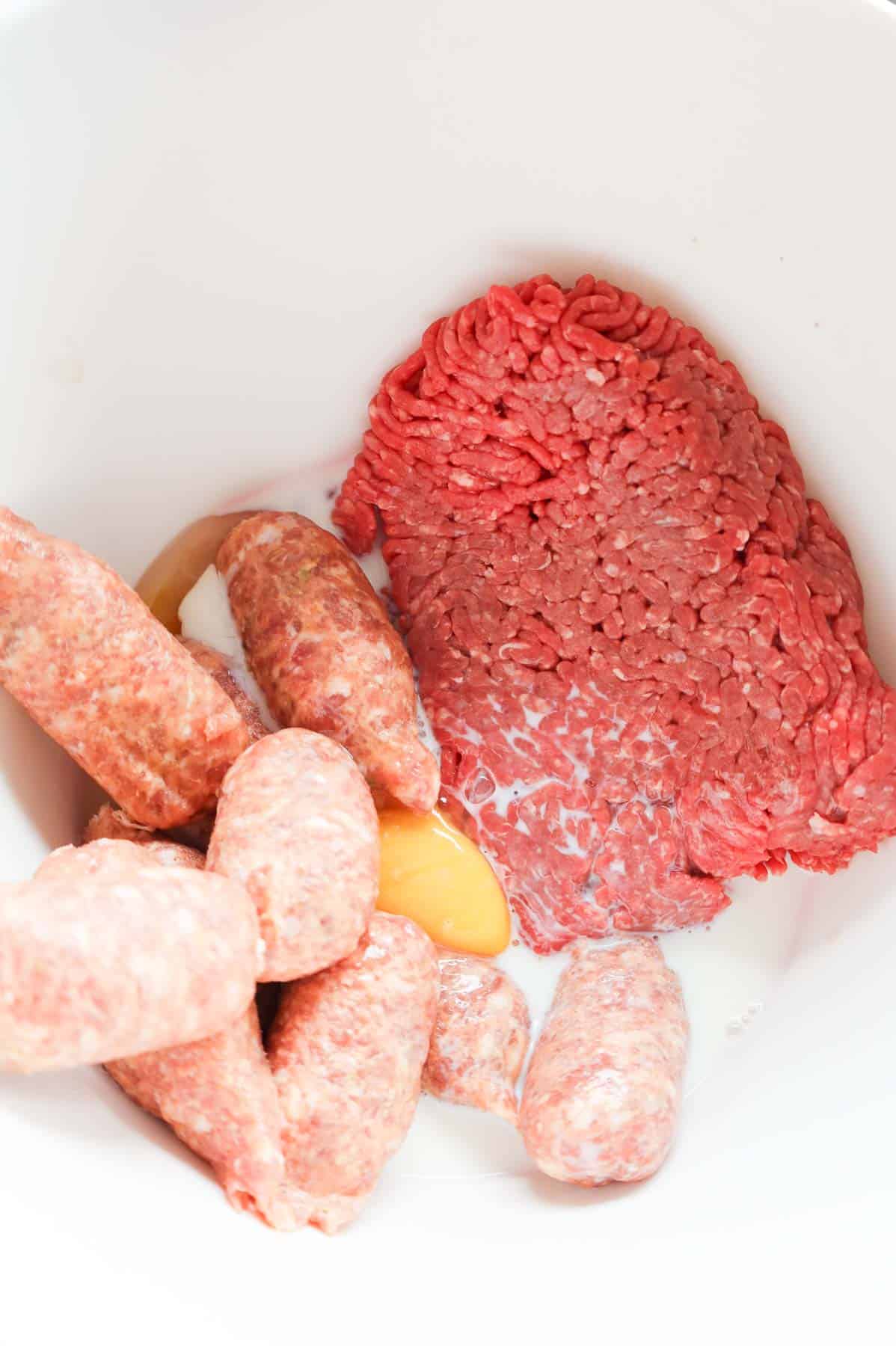 egg, milk, sausage meat and ground beef in a mixing bowl