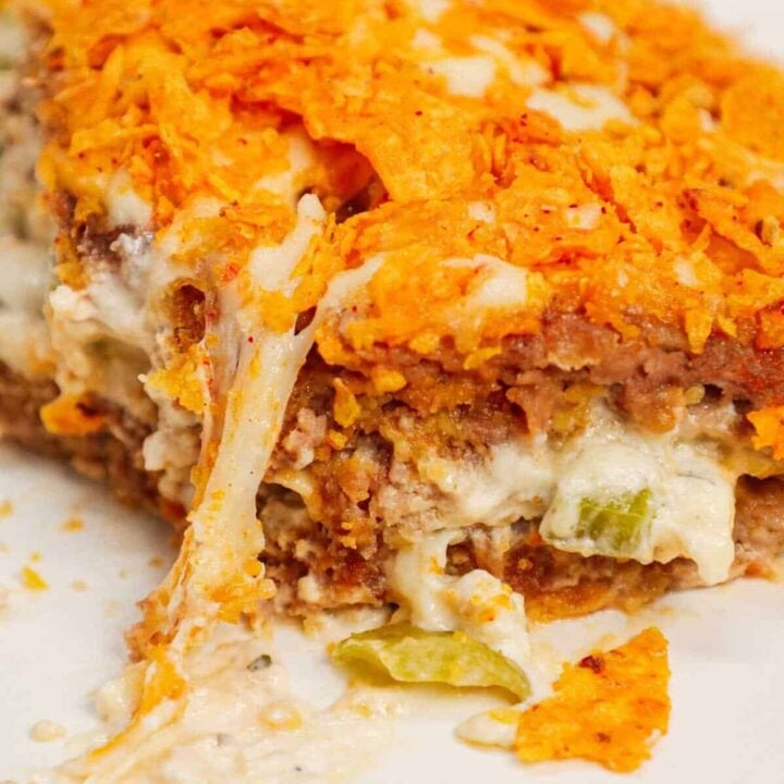 Dorito Meatloaf Casserole is a hearty dish with layers of ground beef and sausage meatloaf loaded with crushed Doritos, a cream cheese and ranch dressing filling and topped with cheese and more crushed Doritos.