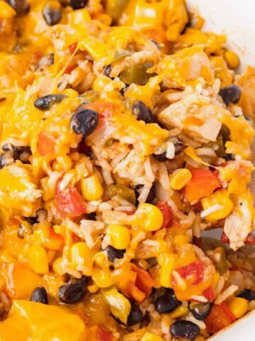 Fiesta Chicken Casserole is a hearty chicken and rice casserole loaded with diced bell peppers, Rotel, black beans, corn and cheddar cheese.