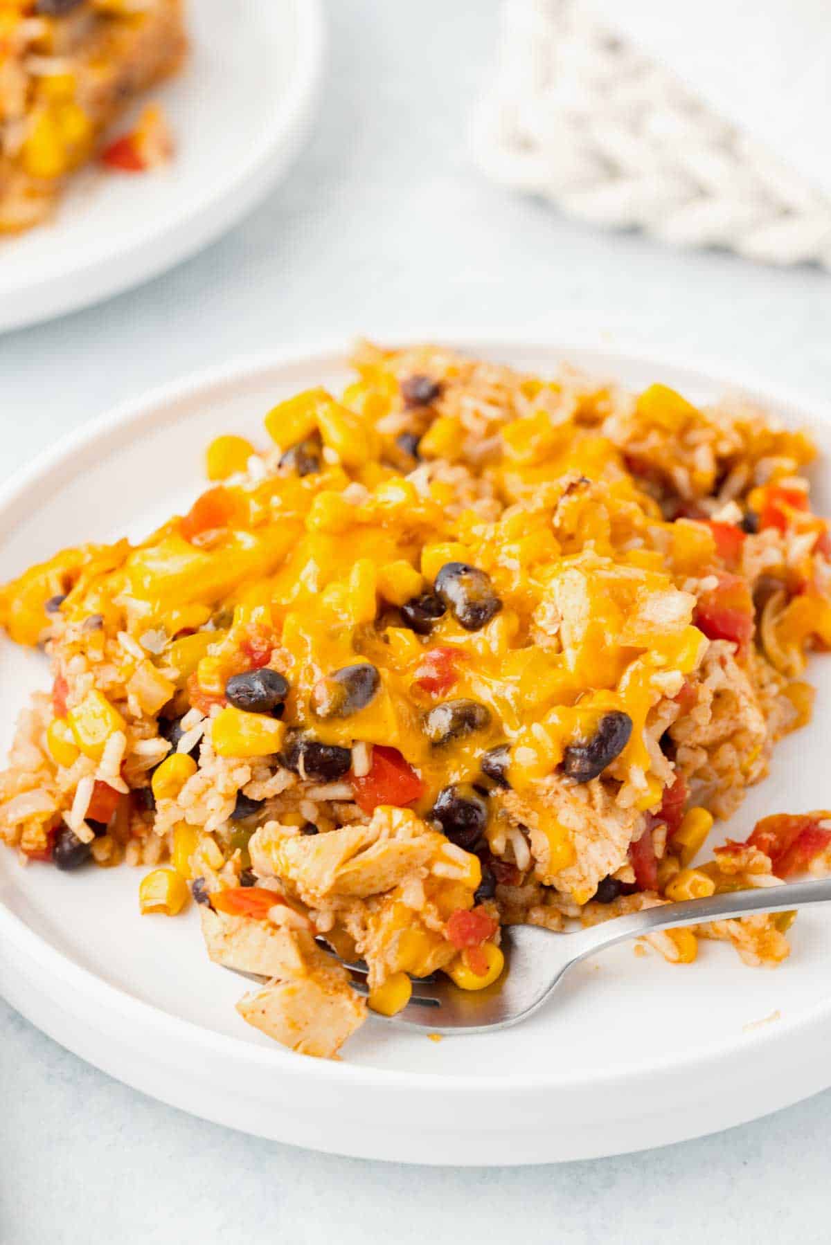 Fiesta Chicken Casserole is a hearty chicken and rice casserole loaded with diced bell peppers, Rotel, black beans, corn and cheddar cheese.