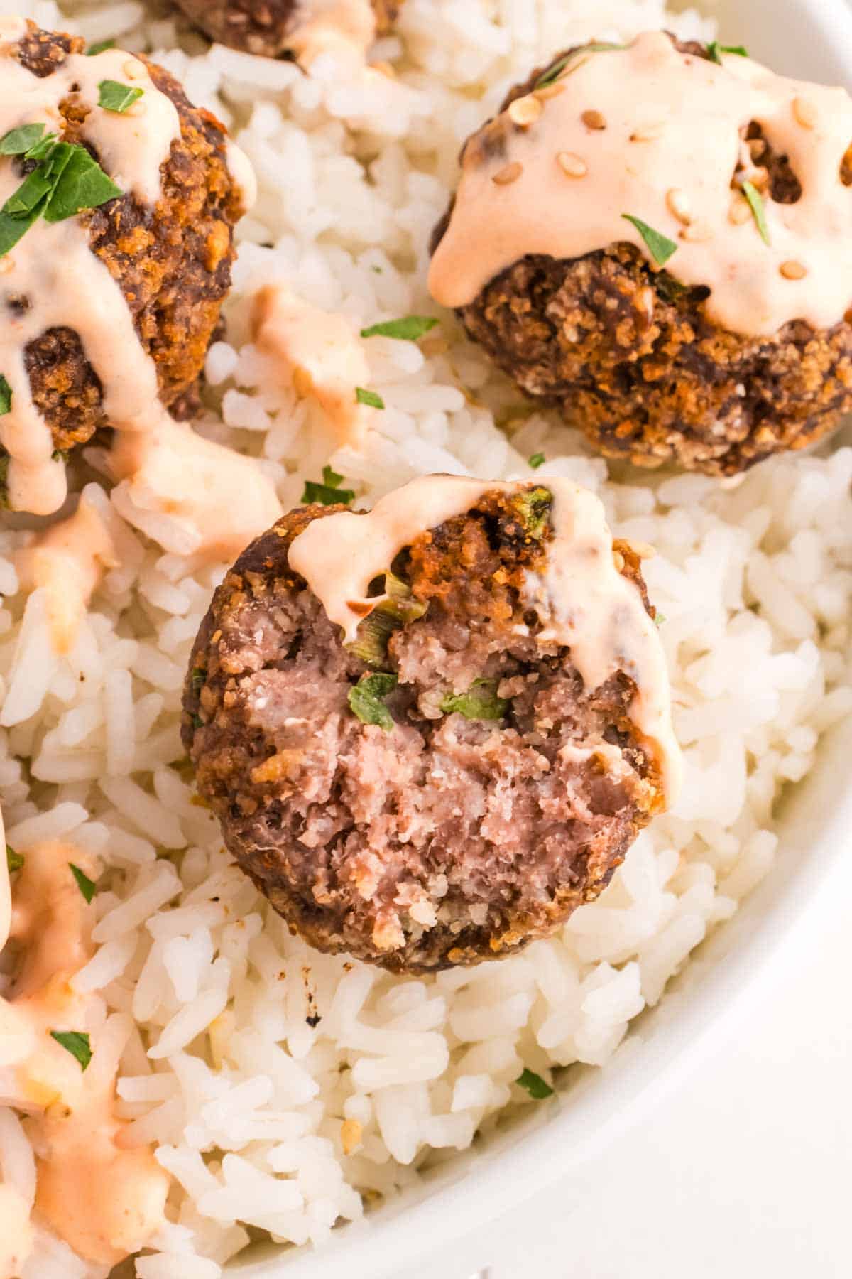 Firecracker Meatballs are flavourful homemade ground beef meatballs with a bit of a kick from siracha sauce and red pepper flakes and topped with a sour cream and mayo based sauce.