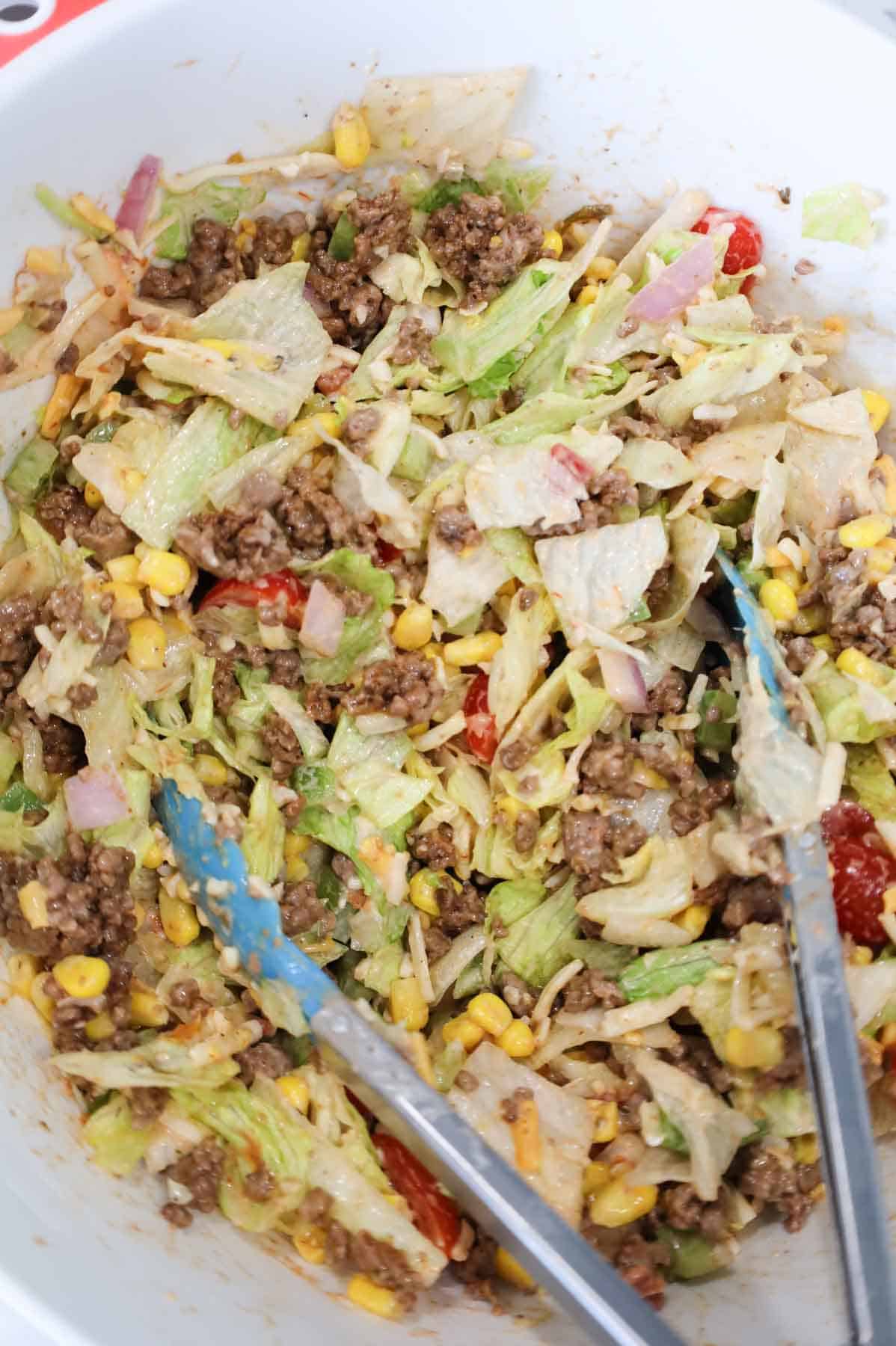 ground beef being tossed with taco salad ingredients