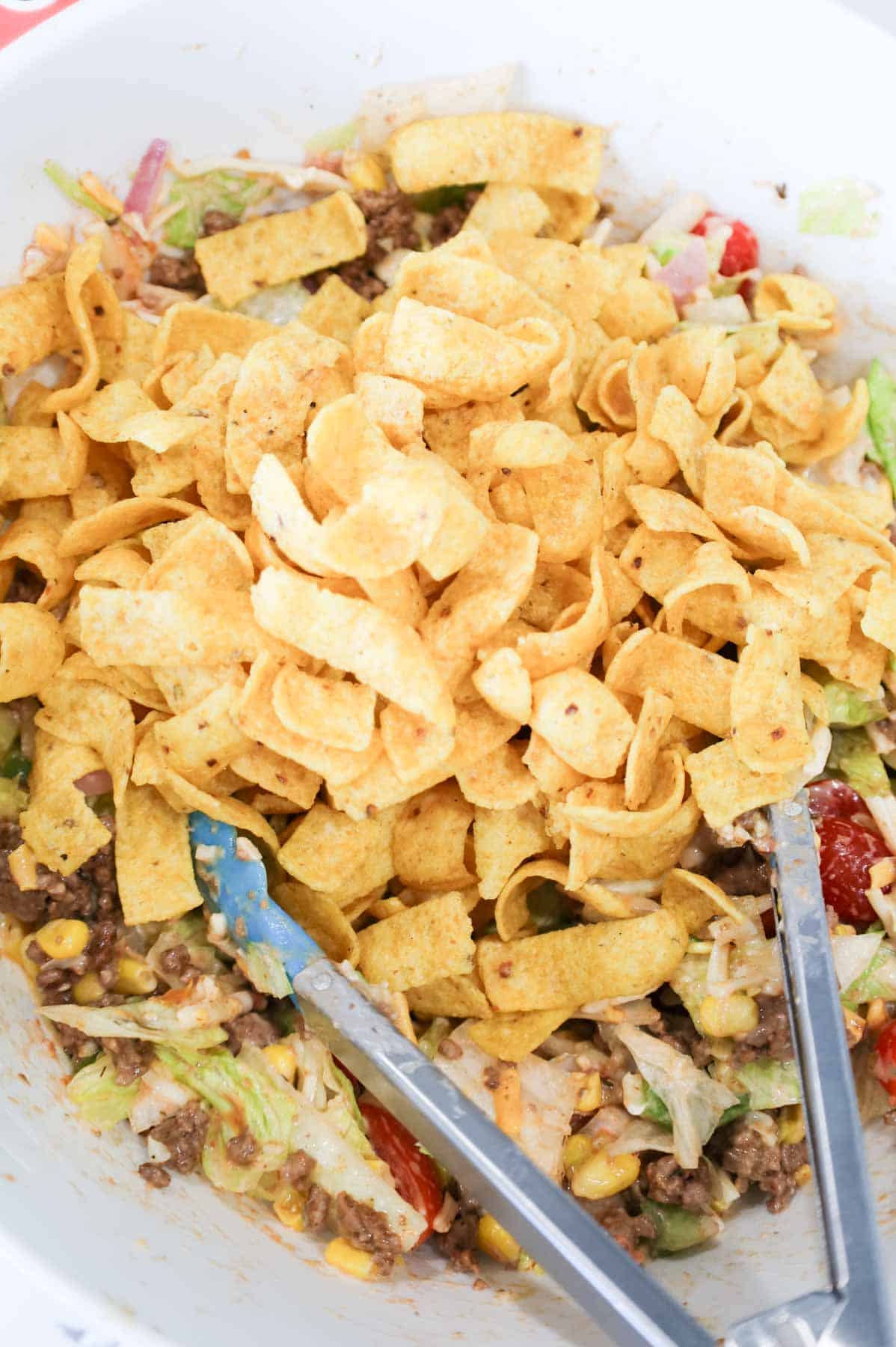corn chips added to bowl with taco salad.