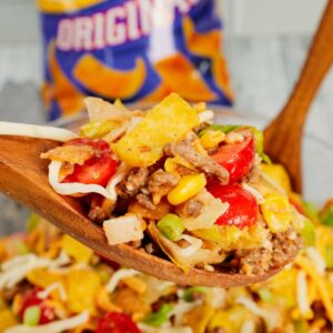 Frito Taco Salad is a delicious meal or side dish recipe loaded with ground beef, taco seasoning, lettuce, red onions, green peppers, grape tomatoes, corn, shredded cheese, salsa, ranch dressing and Fritos corn chips.