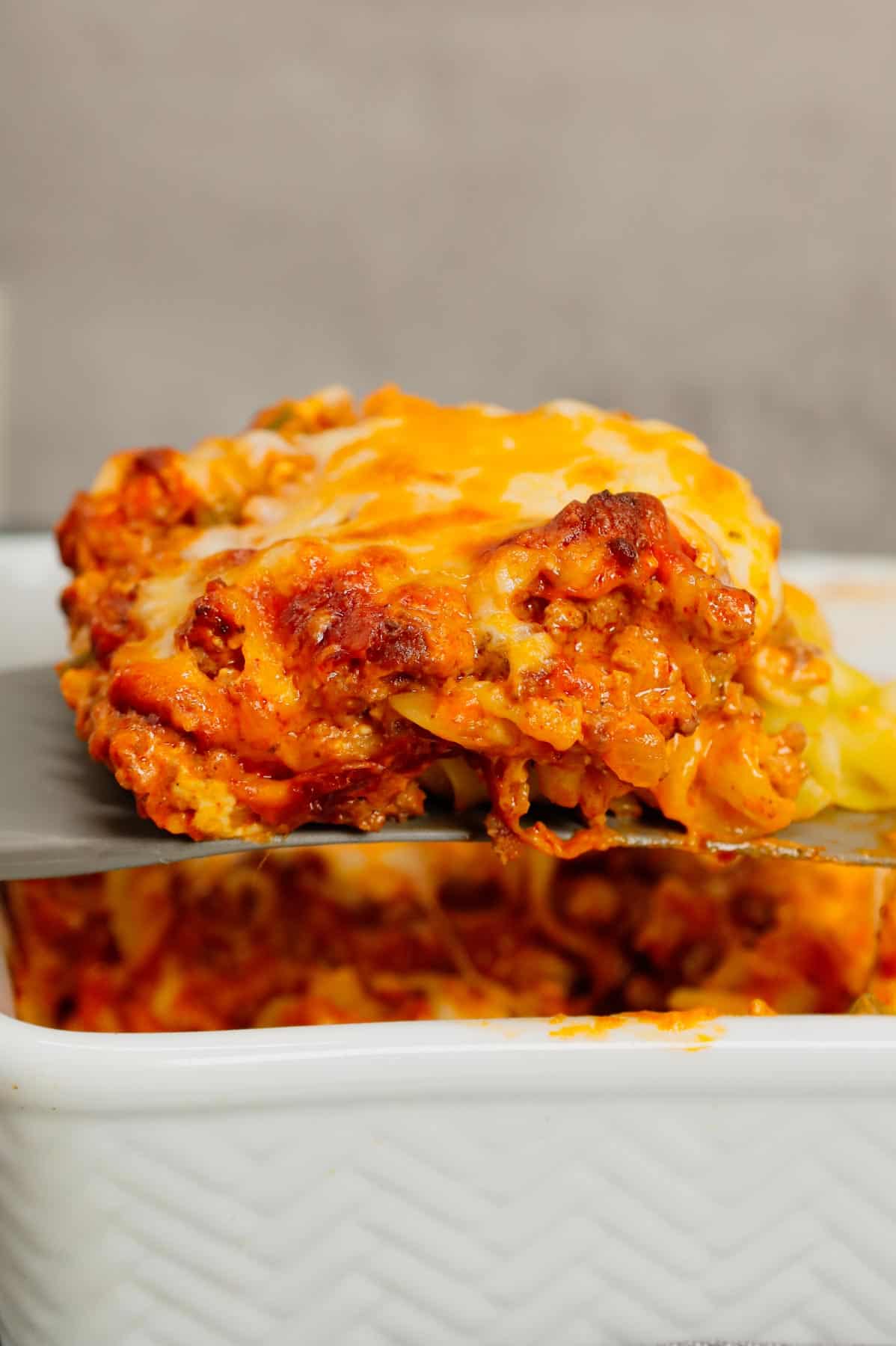 Grandma's Ground Beef Casserole is a simple and classic hamburger dish made with egg noodles, condensed tomato soup, onions, green bell peppers and cream cheese all baked with shredded mozzarella and cheddar on top.