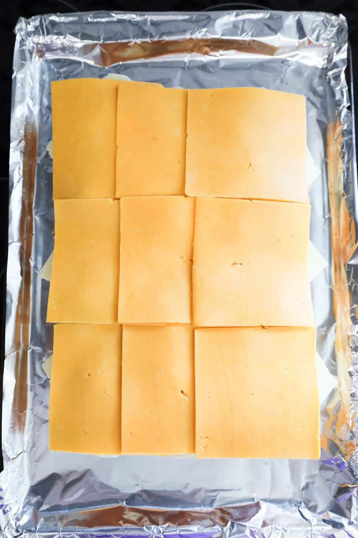 cheddar cheese slices on top of Swiss cheese slices on dinner rolls