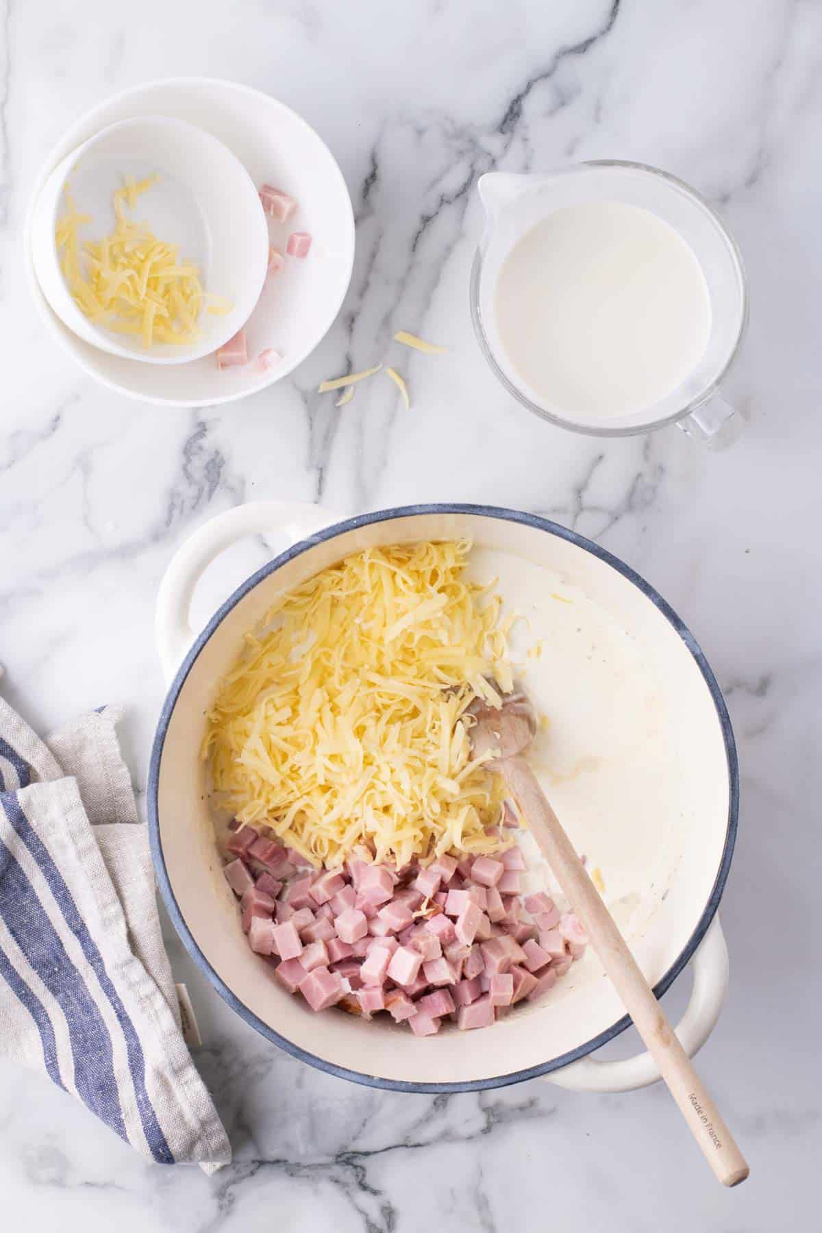 grated cheese and diced ham added to pot with creamy sauce