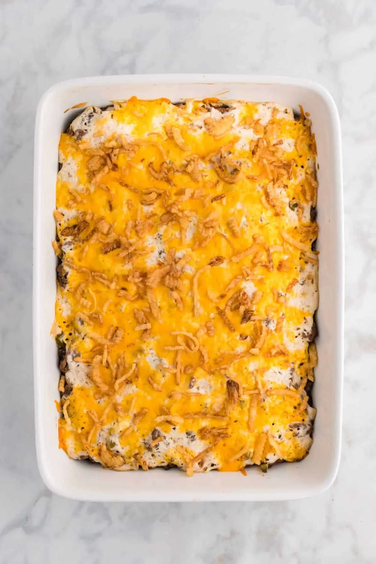 Hobo Casserole is a layered ground beef and sliced potato casserole loaded with diced bell peppers, onions, sour cream, cream of mushroom soup, cheddar cheese and French's crispy fried onions.