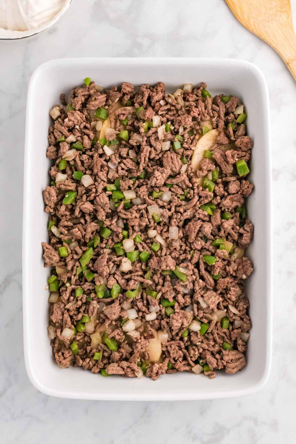 ground beef mixture on top of potatoes in a baking dish