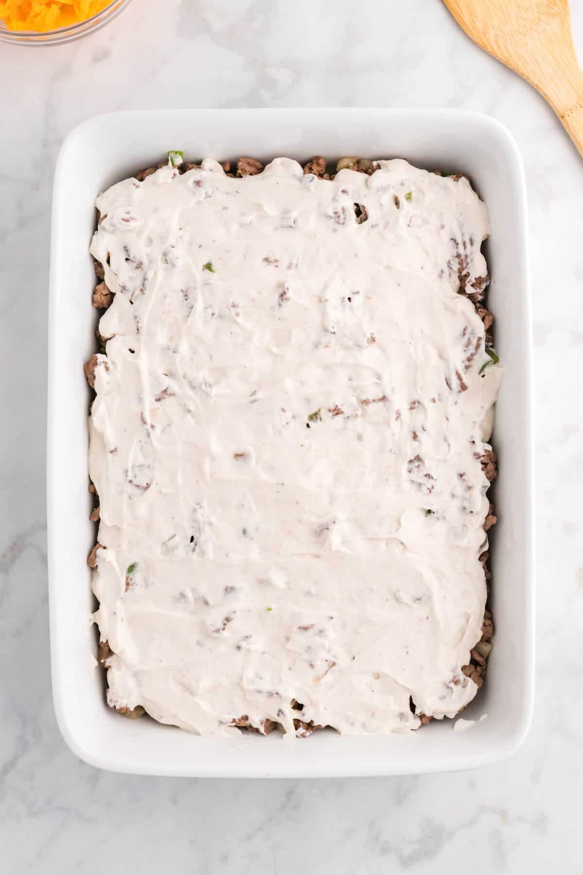 sour cream and cream of mushroom soup mixture spread over ground beef in a baking dish