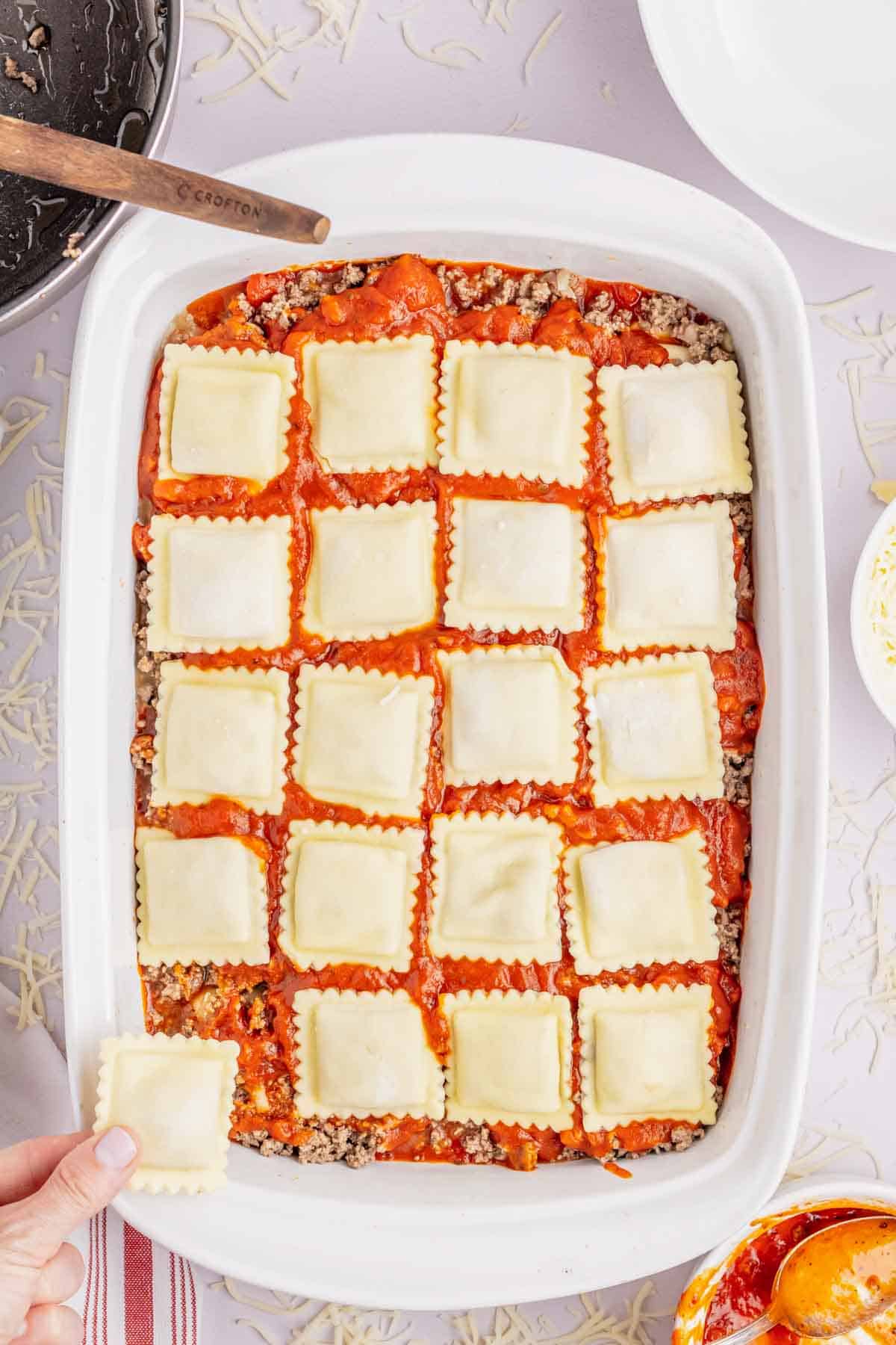 layers of frozen ravioli, marinara and ground beef in a baking dish