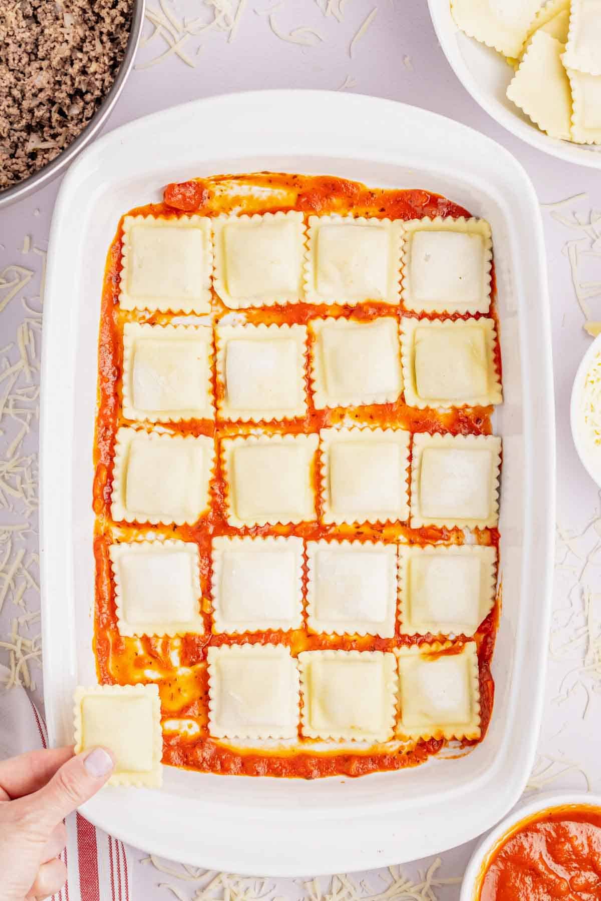 frozen ravioli on top of marinara sauce in the bottom of a baking dish