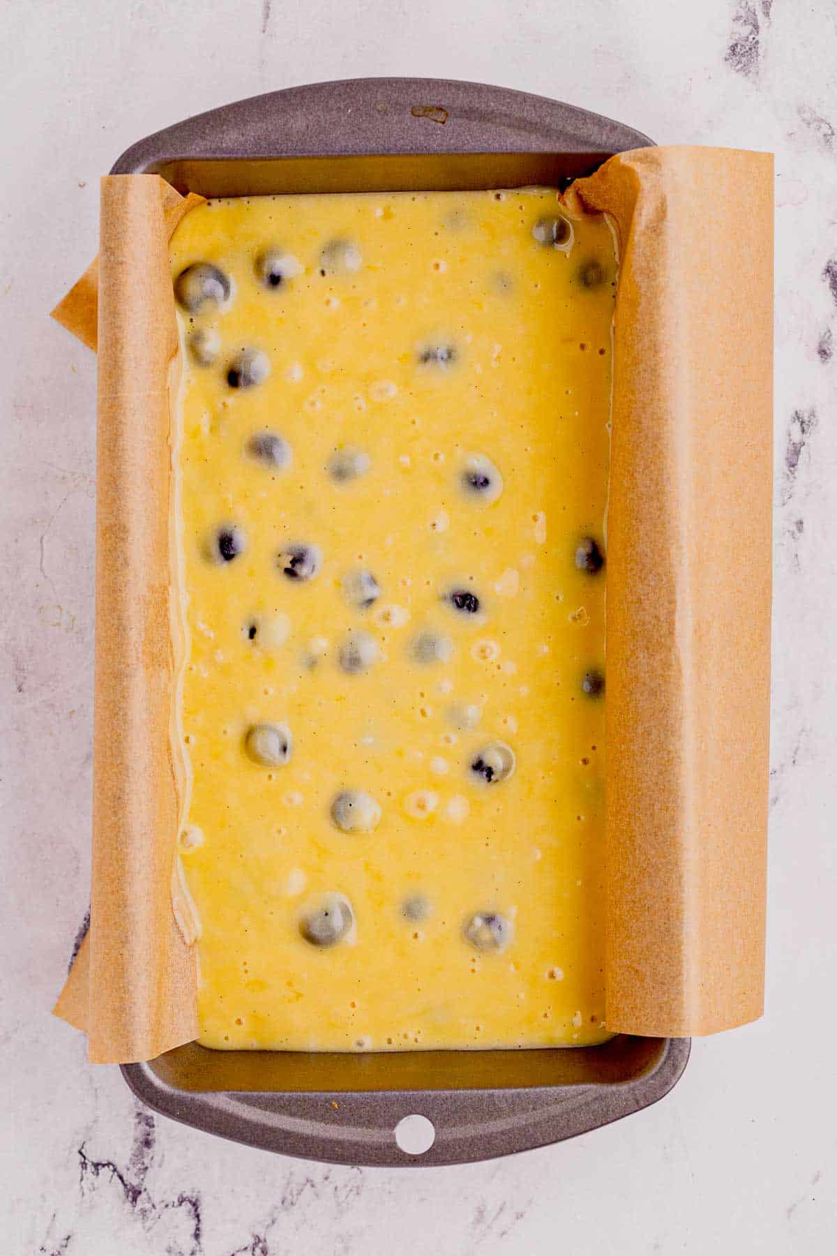 blueberry lemon loaf batter in a parchment lined loaf pan