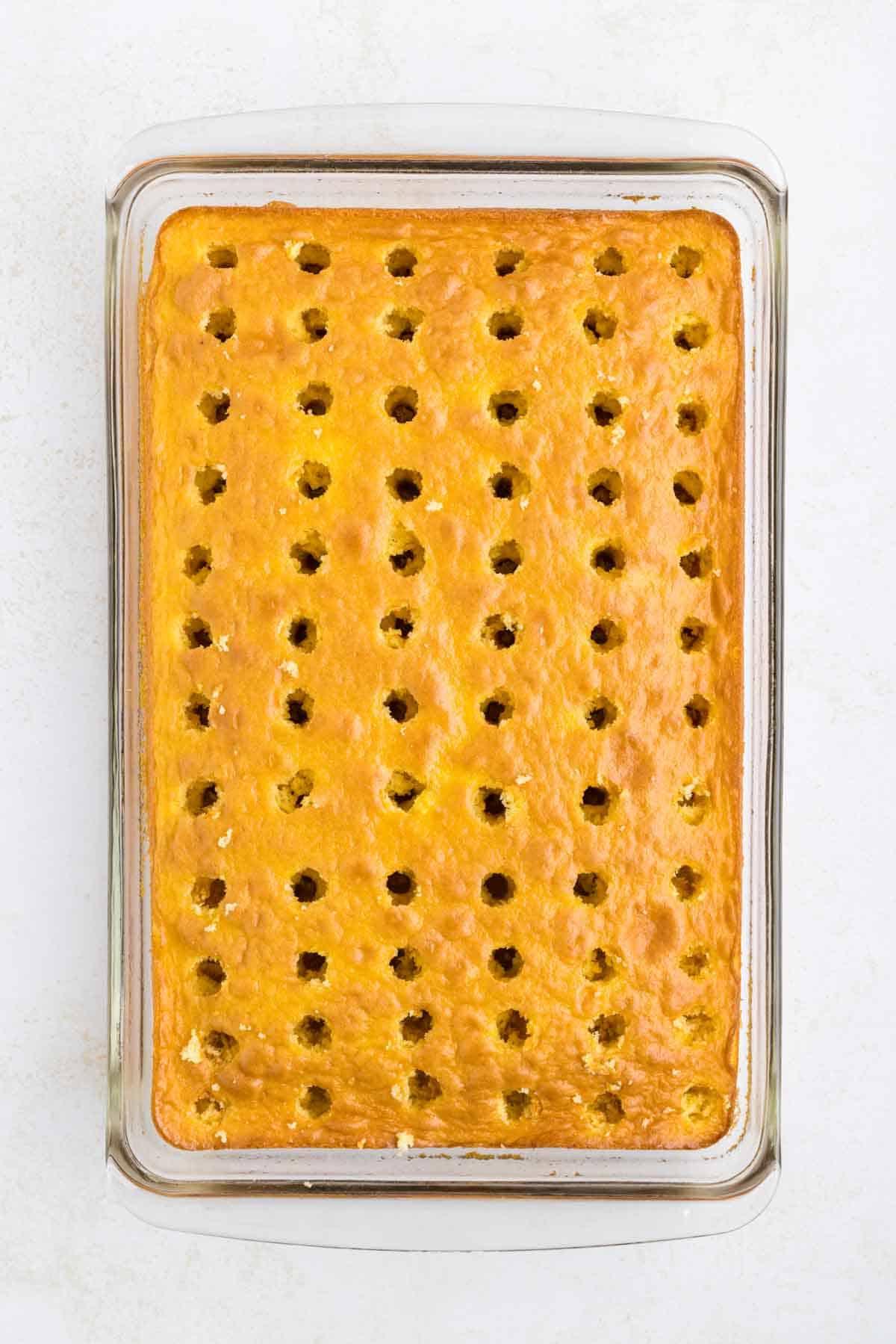 rows of holes poked in a lemon cake