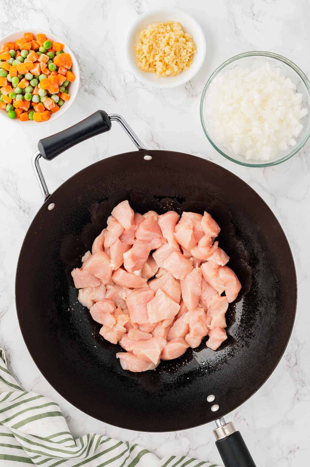 raw chicken breast chunks in a wok