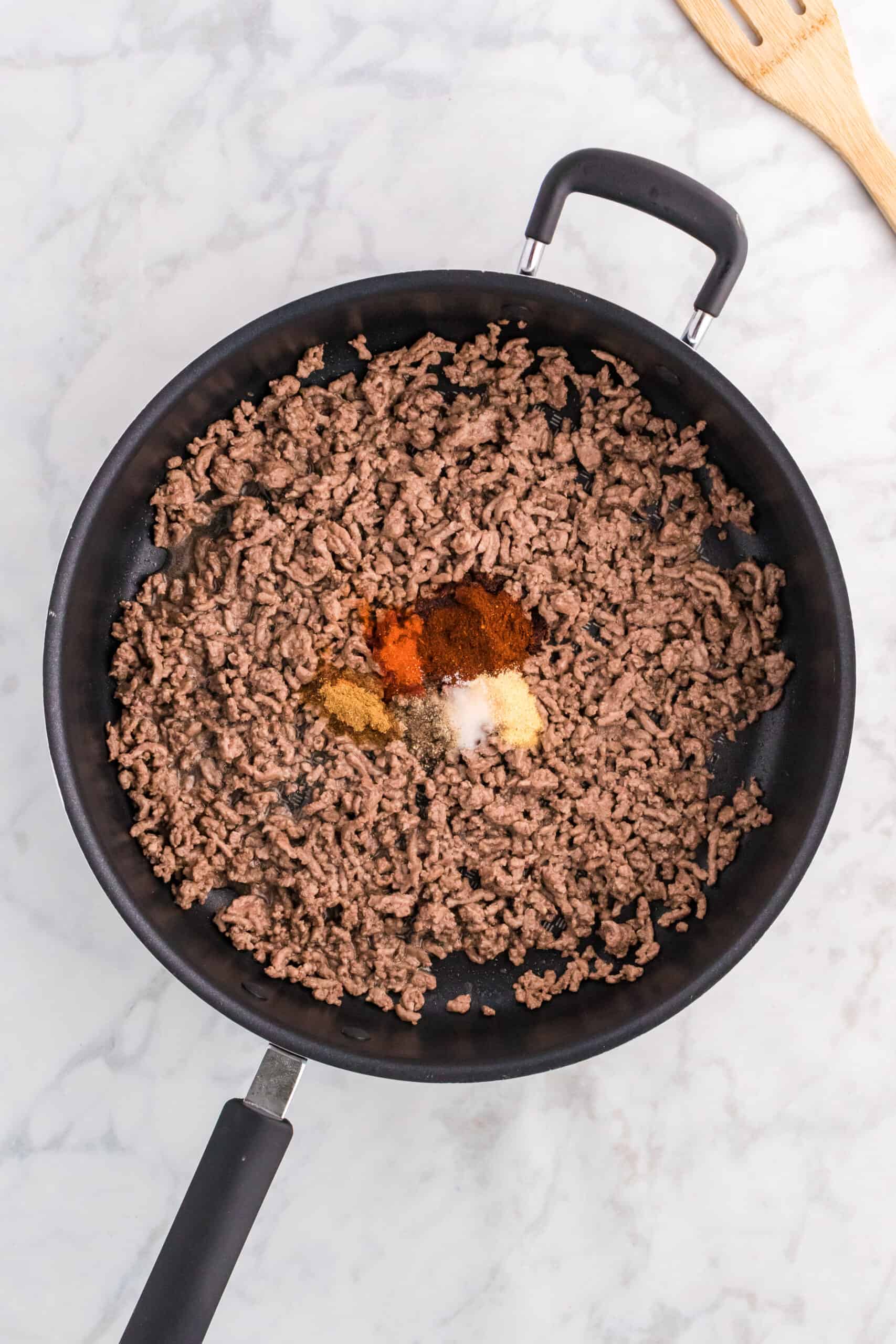 spices on top of cooked ground beef in a skillet