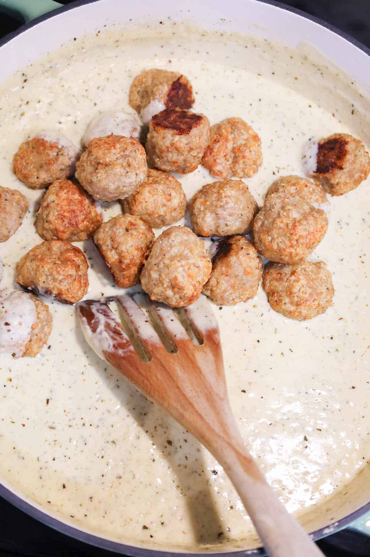 cooked chicken meatballs added to skillet with alfredo sauce