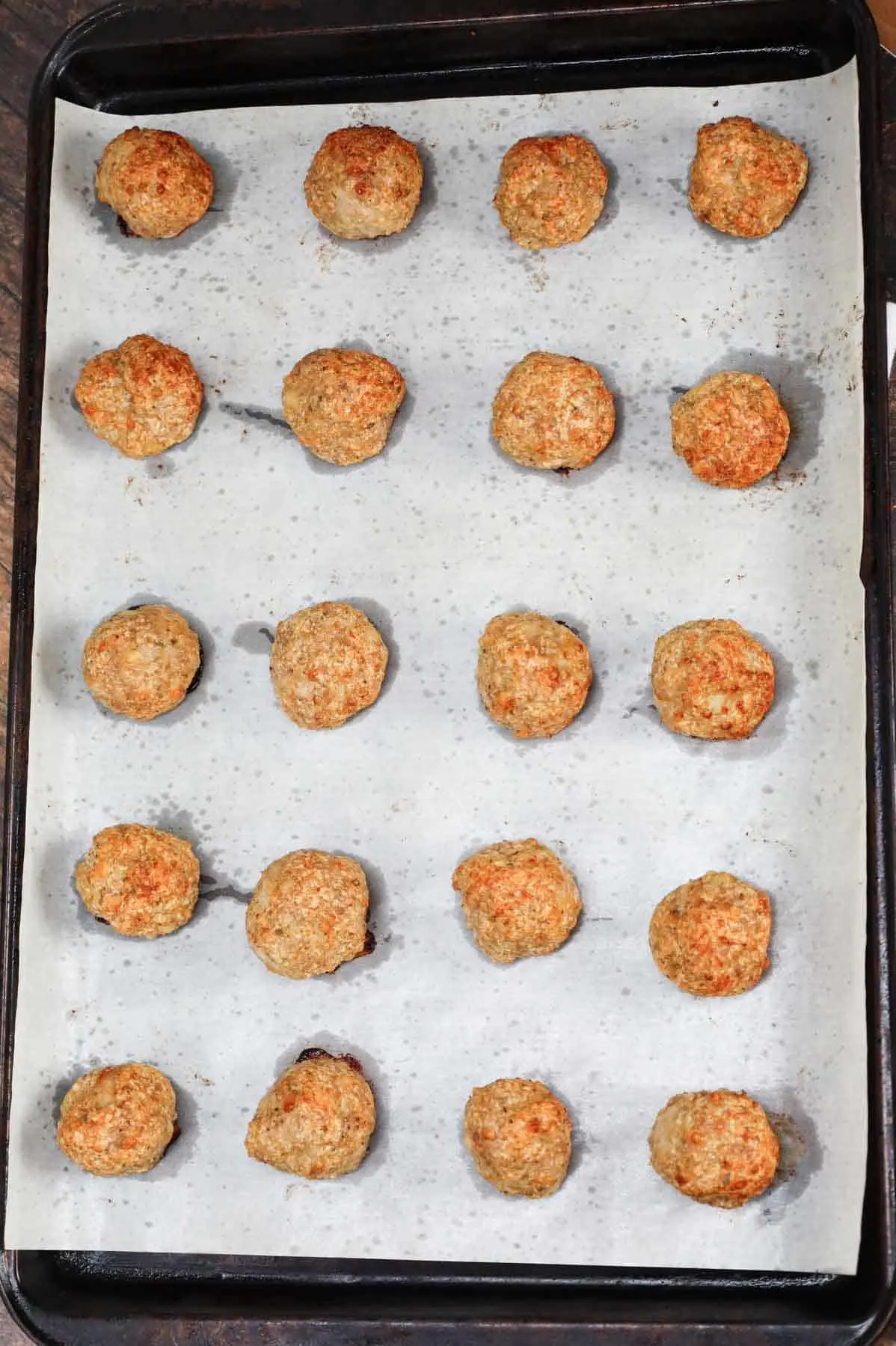 cooked chicken meatballs on a parchment lined baking sheet