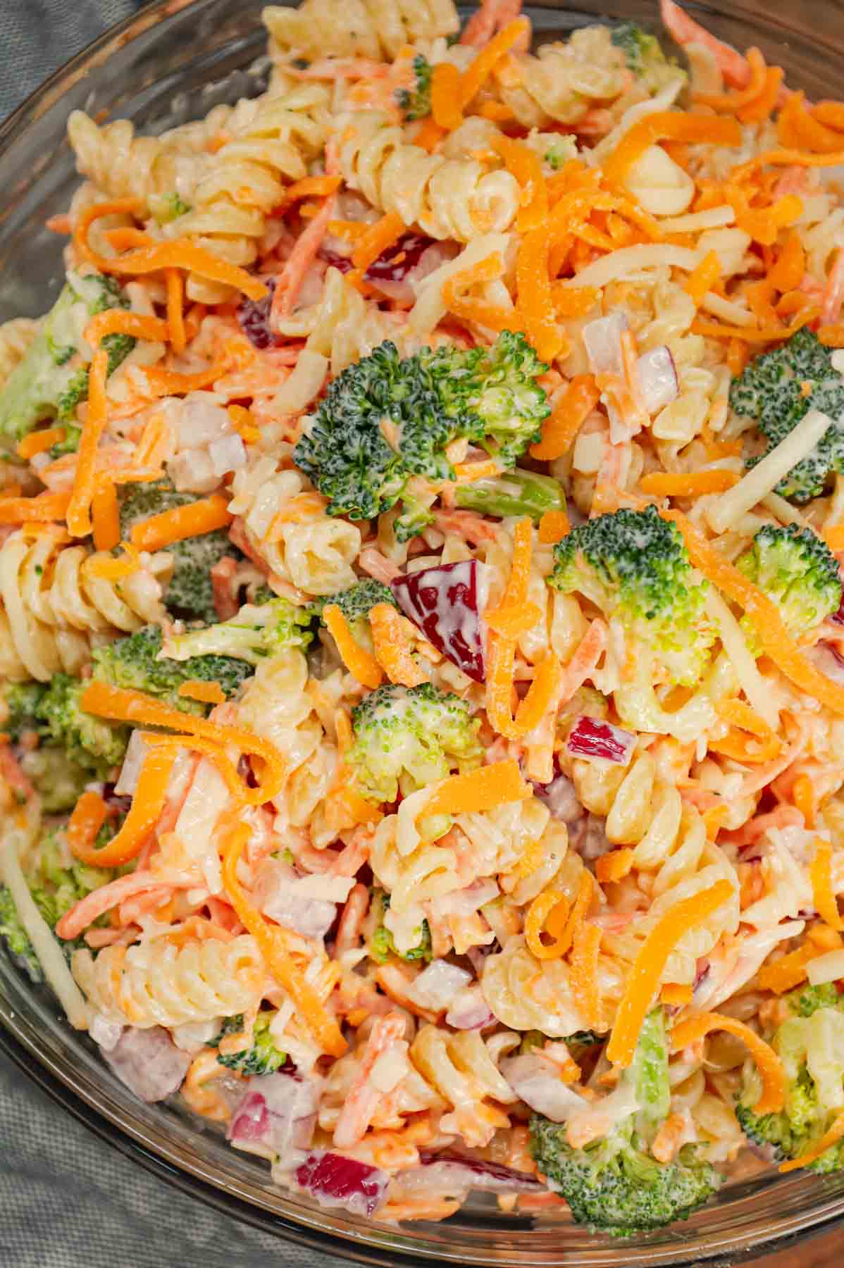 Broccoli Cheddar Pasta Salad is a tasty cold side dish recipe loaded with rotini pasta, broccoli florets, red onions, shredded carrots, cheddar cheese and parmesan all tossed in a mayo and ranch dressing mixture.