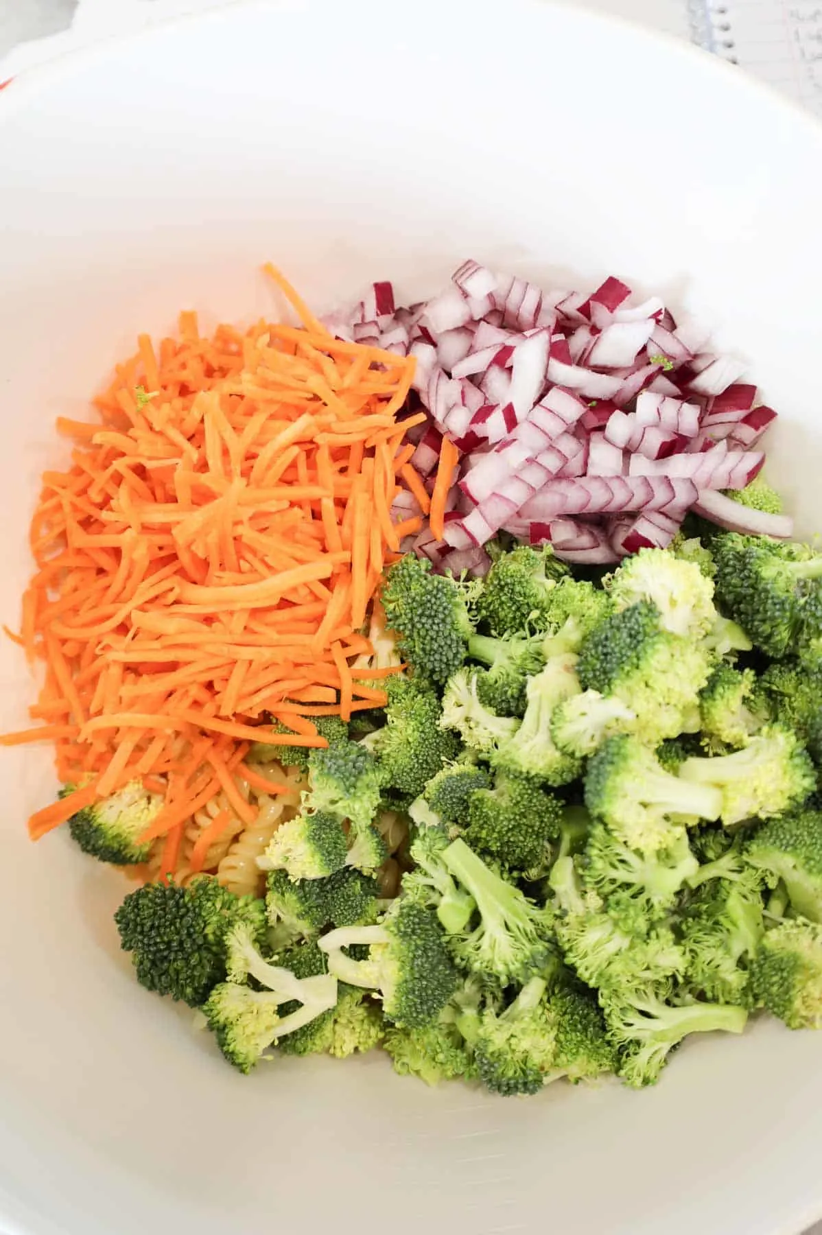 shredded carrots, diced red onions and chopped broccoli florets in a mixing bowl