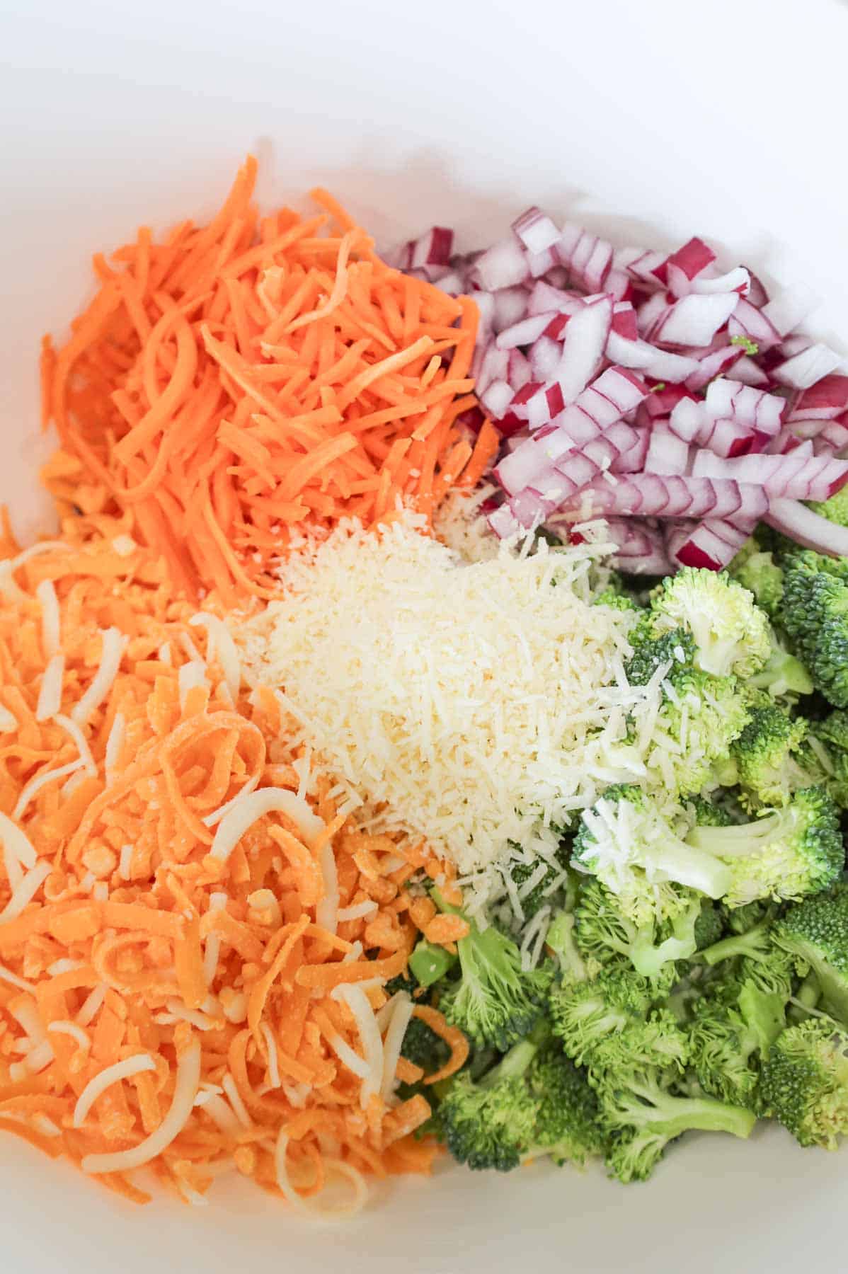 shredded cheese, diced red onions, shredded carrots and chopped broccoli florets in a mixing bowl