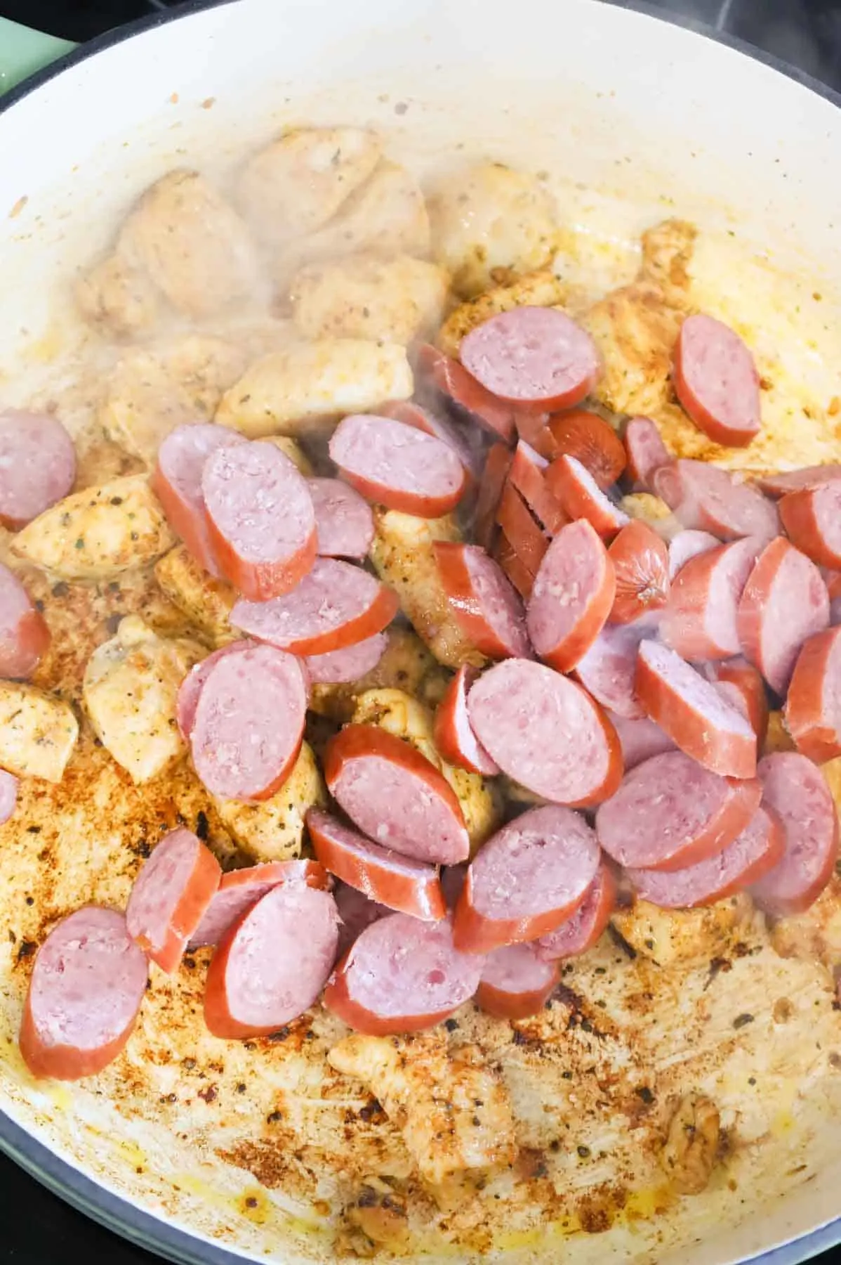 smoked sausage slices added to skillet with chicken breast chunks