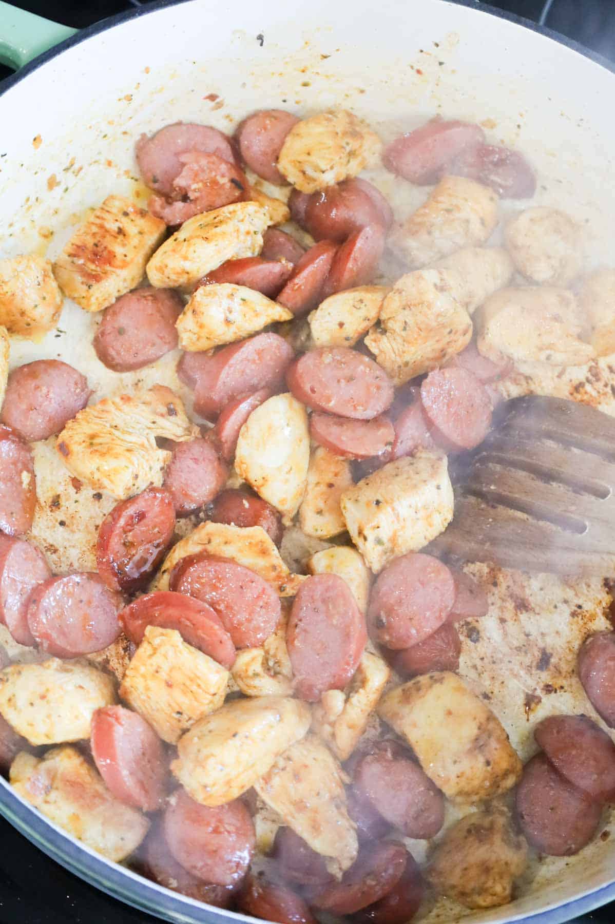 sliced smoked sausage and chicken breast chunks cooking in a skillet
