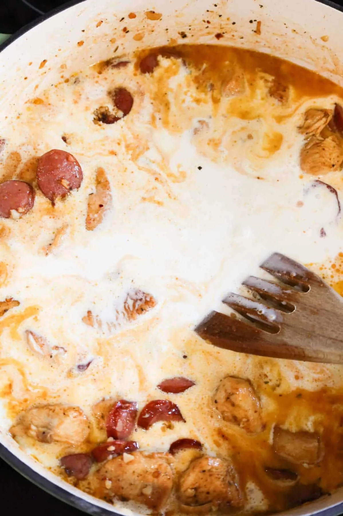 heavy cream added to skillet with cooked sausage and chicken breast chunks