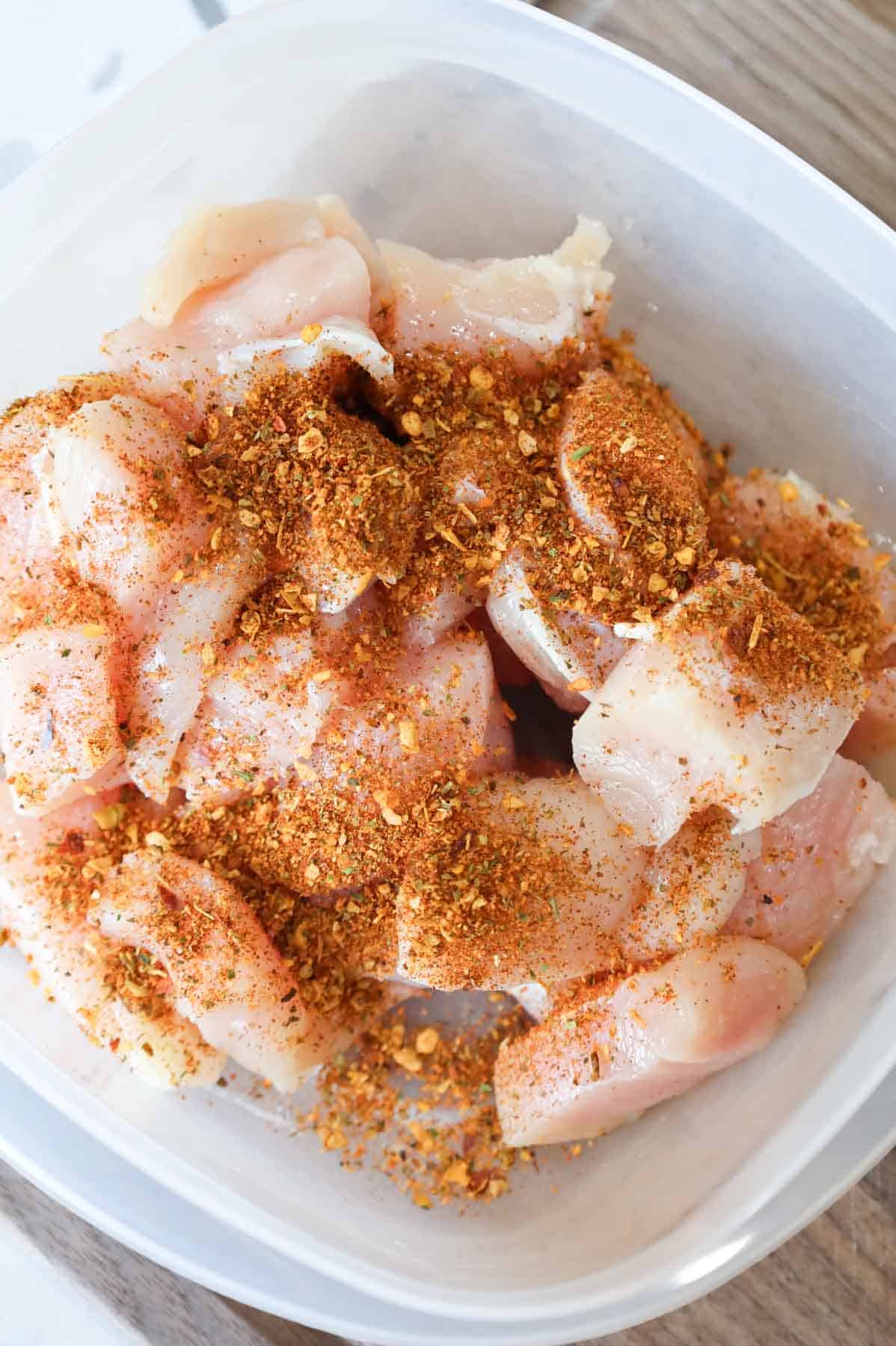 Cajun seasoning on top of chicken breast chunks in a bowl