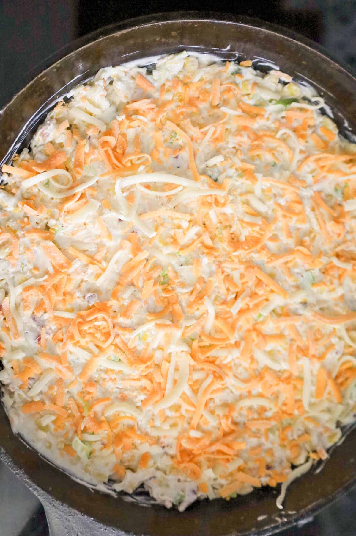 shredded cheese on top of corn dip in a skillet