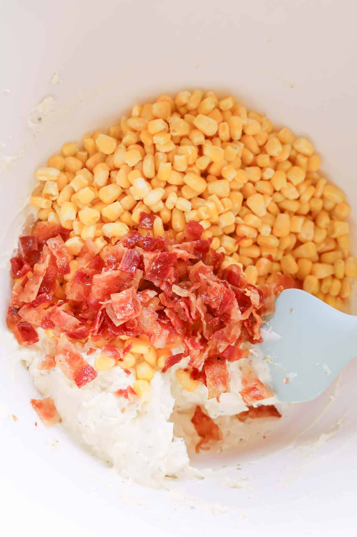chopped bacon and corn on top of sour cream mixture in a bowl