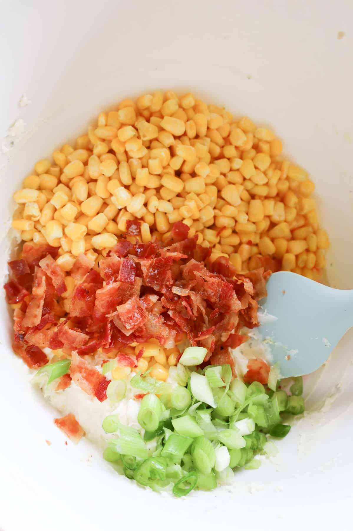 green onions, chopped bacon and corn on top of cream cheese mixture in a bowl