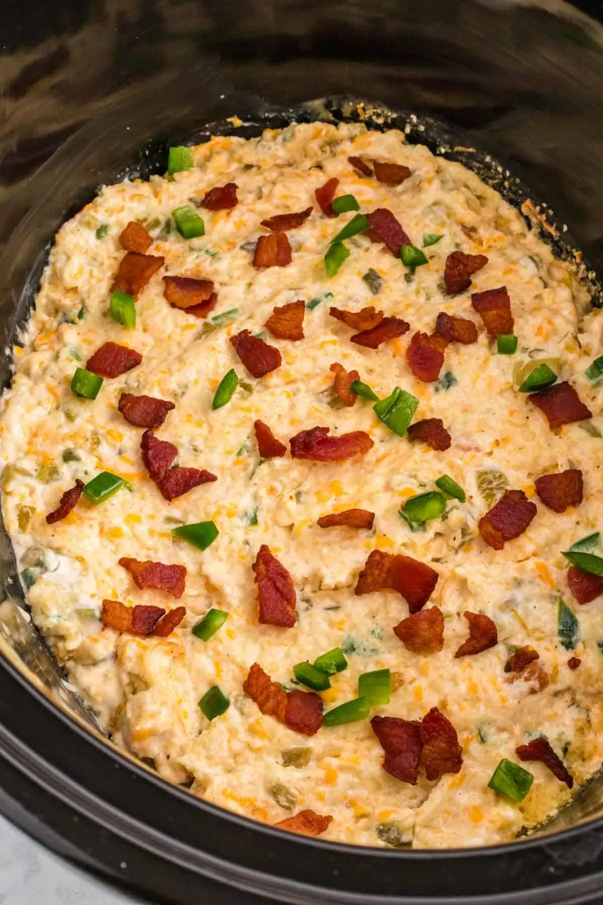 Crock Pot Jalapeno Popper Dip is a delicious hot dip recipe loaded with cream cheese, cheddar, Monterey Jack, mayo, sour cream, jalapenos, green chilies, parmesan, panko bread crumbs and bacon.