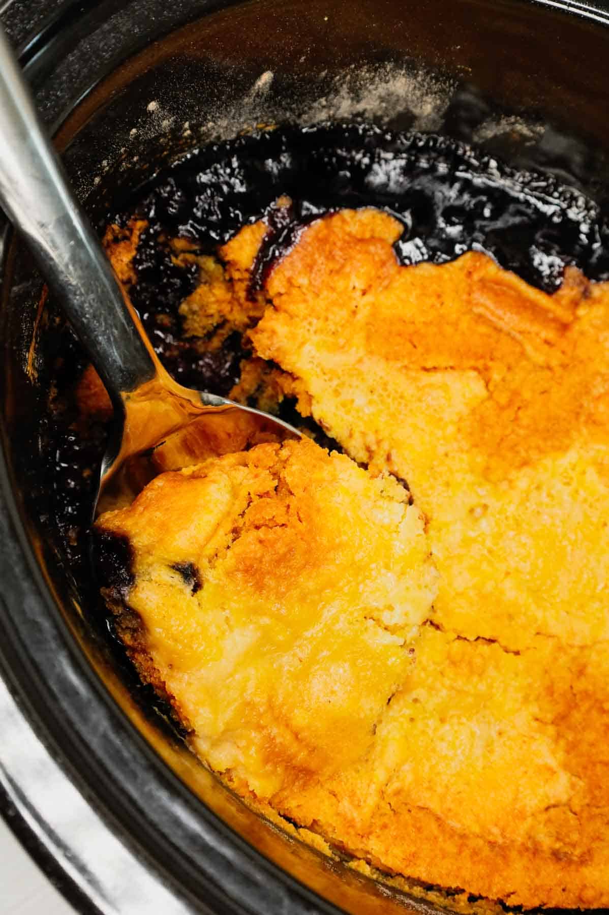 Crock Pot Lemon Blueberry Cobbler is an easy slow cooker dessert recipe using frozen blueberries, lemon pudding mix, sugar, boxed lemon cake mix and butter.