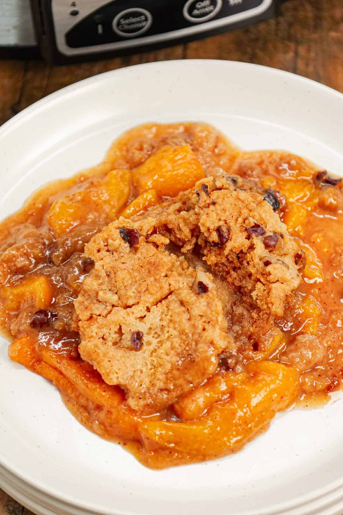Crock Pot Peach Cobbler with Cake Mix is an easy slow cooker dessert recipe using canned peach slices, boxed butter pecan cake mix, brown sugar, cinnamon, butter and chopped pecans.